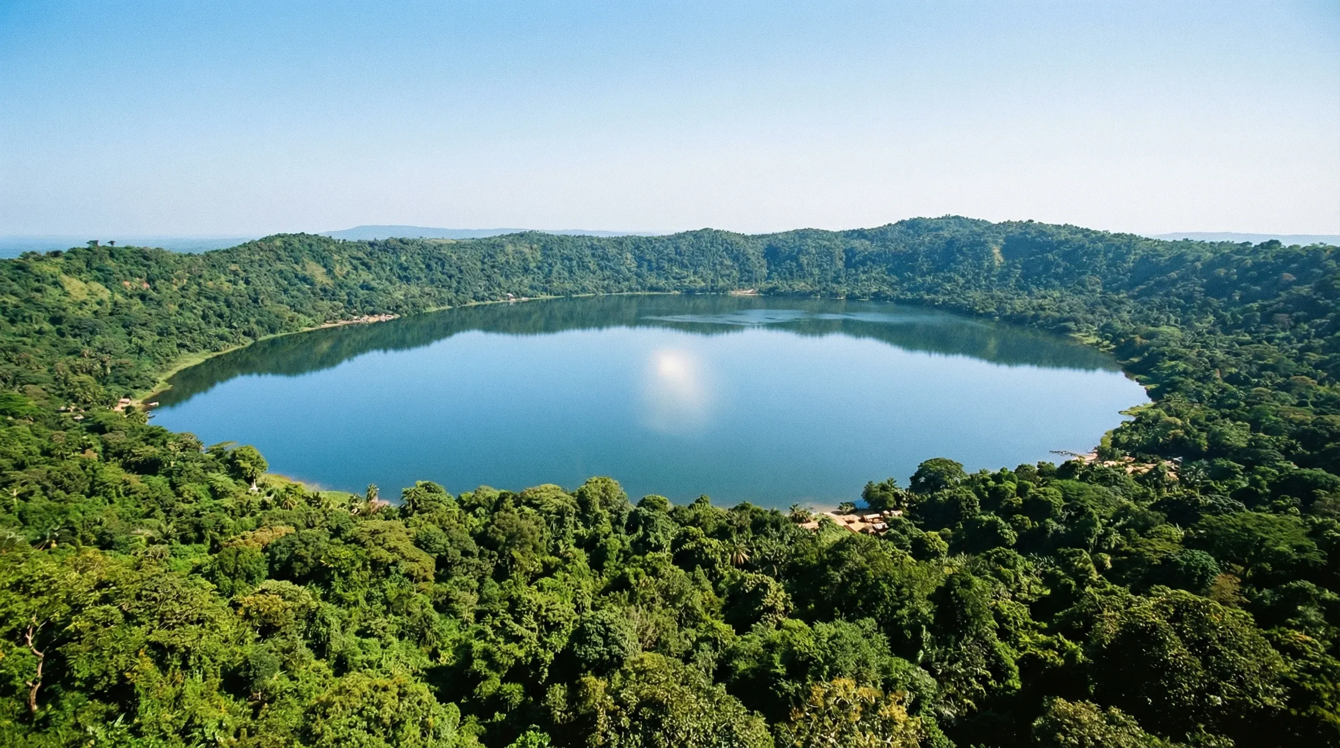 An elevated view of the circular Lake Bosomtwe surrounded by lush green tropical hills in the Ashanti Region.