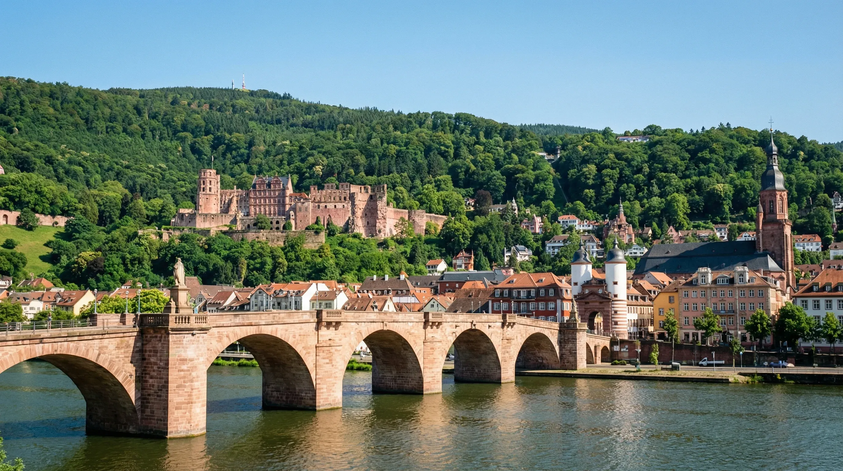 A wide view of the historic Heidelberg Castle and the stone Old Bridge spanning the Neckar River in Germany.