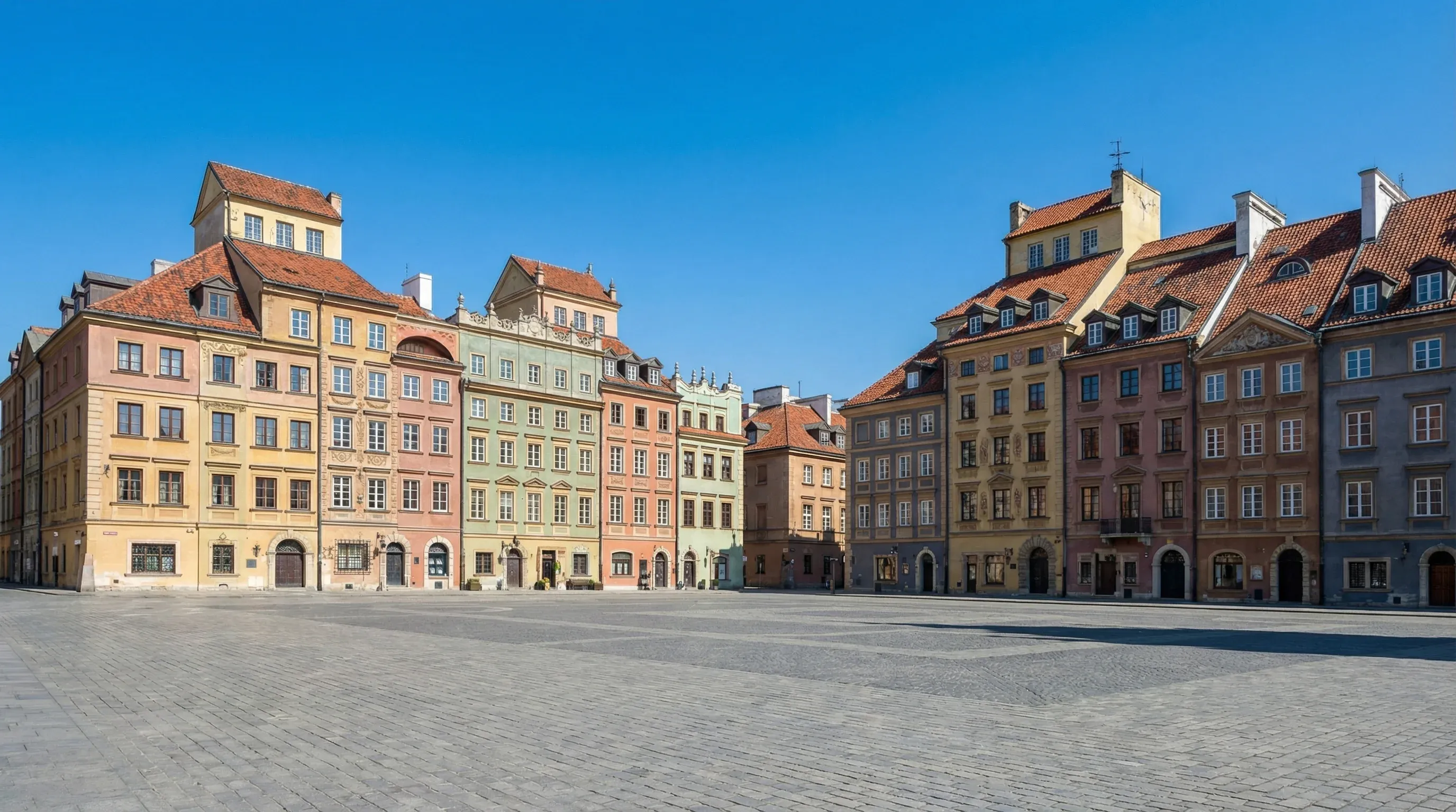 Rows of colorful historic burgher houses surrounding the cobblestone Market Place in Warsaw's Old Town on a clear day.
