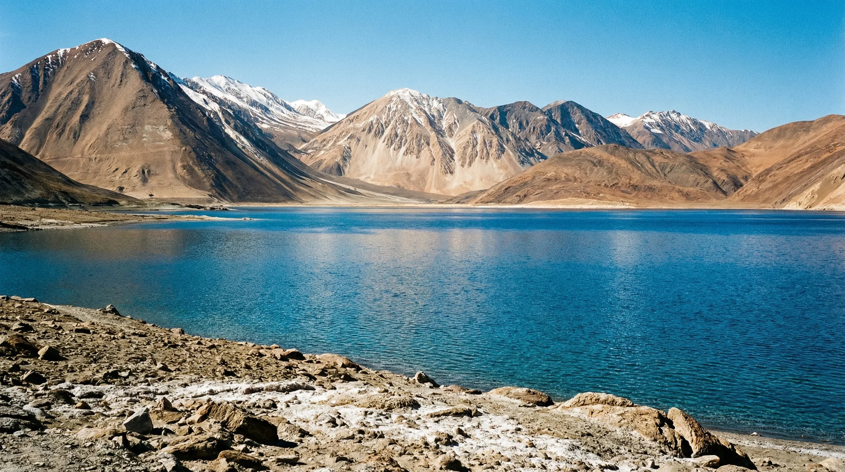 The deep blue waters of Pangong Tso lake in Ladakh, framed by snow-capped Himalayan mountains.