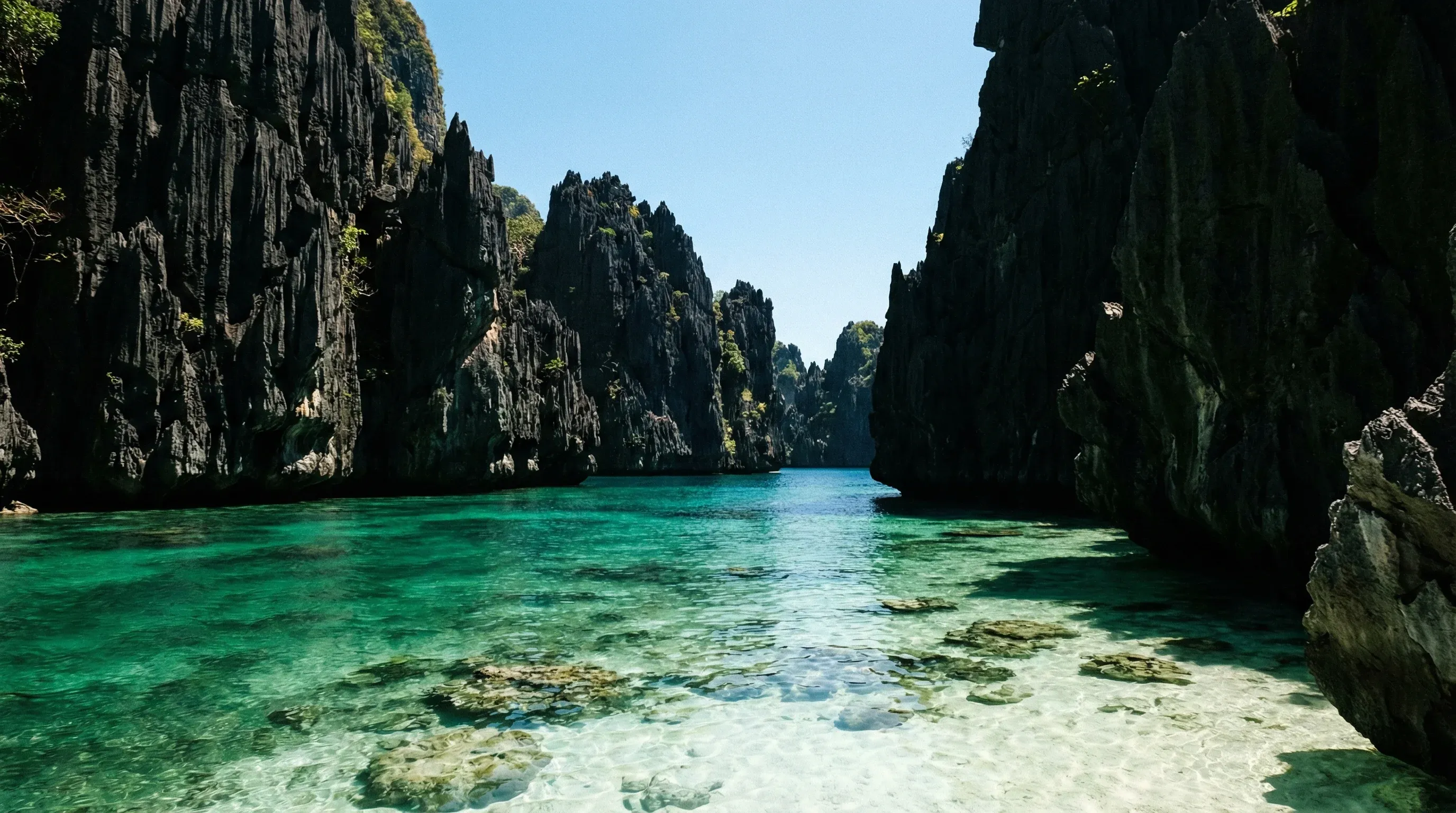 Dramatic limestone cliffs surrounding a calm, emerald-colored lagoon in El Nido, Palawan.