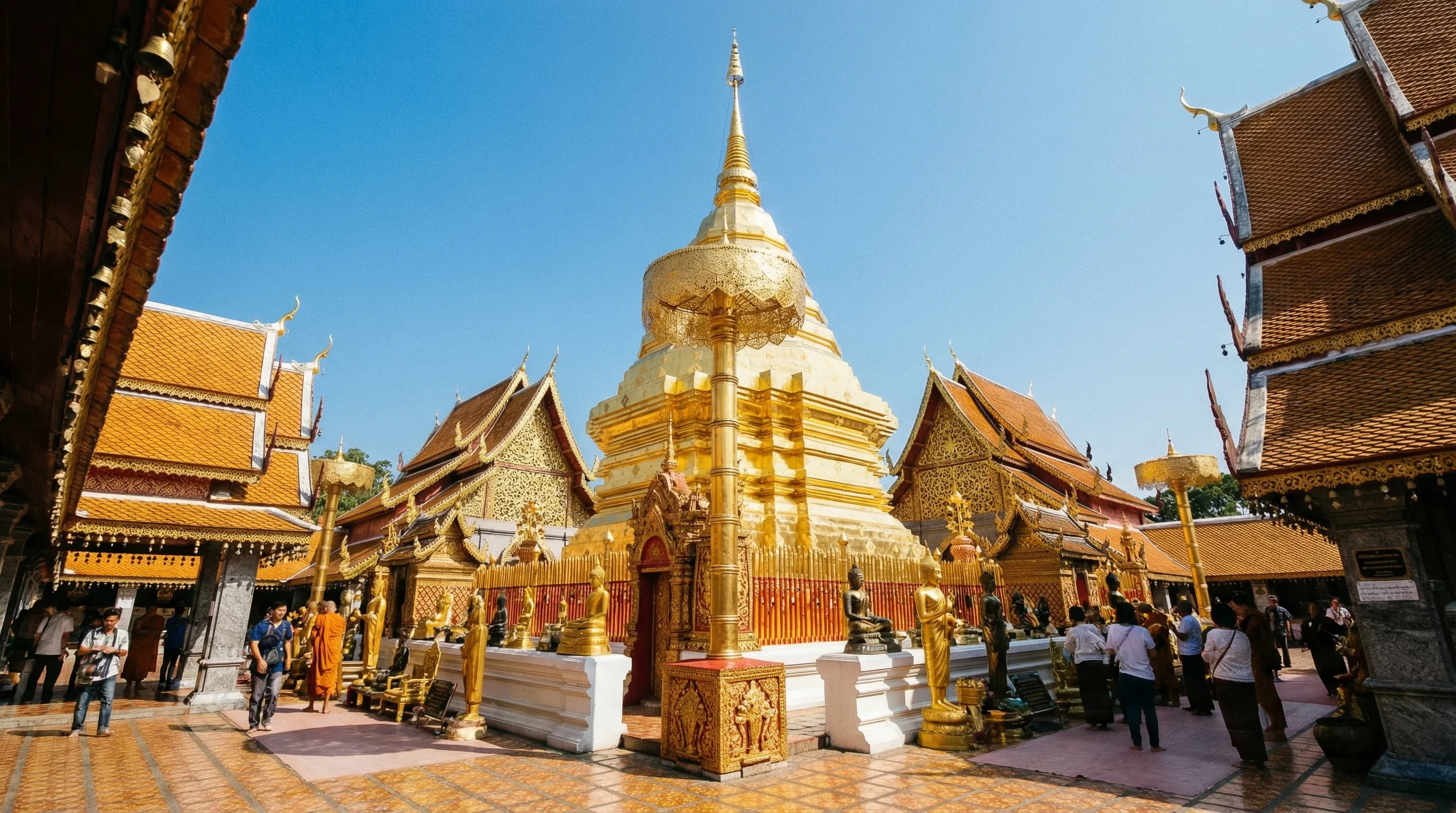 The central golden chedi of Wat Phra That Doi Suthep temple in Chiang Mai under a bright midday sun.