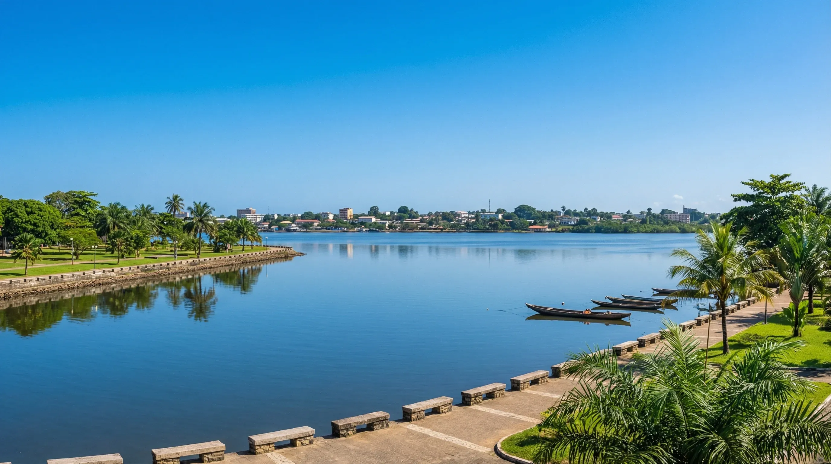 A wide-angle view of the palm-lined coastal promenade in Libreville, overlooking the calm waters of the Komo River estuary.