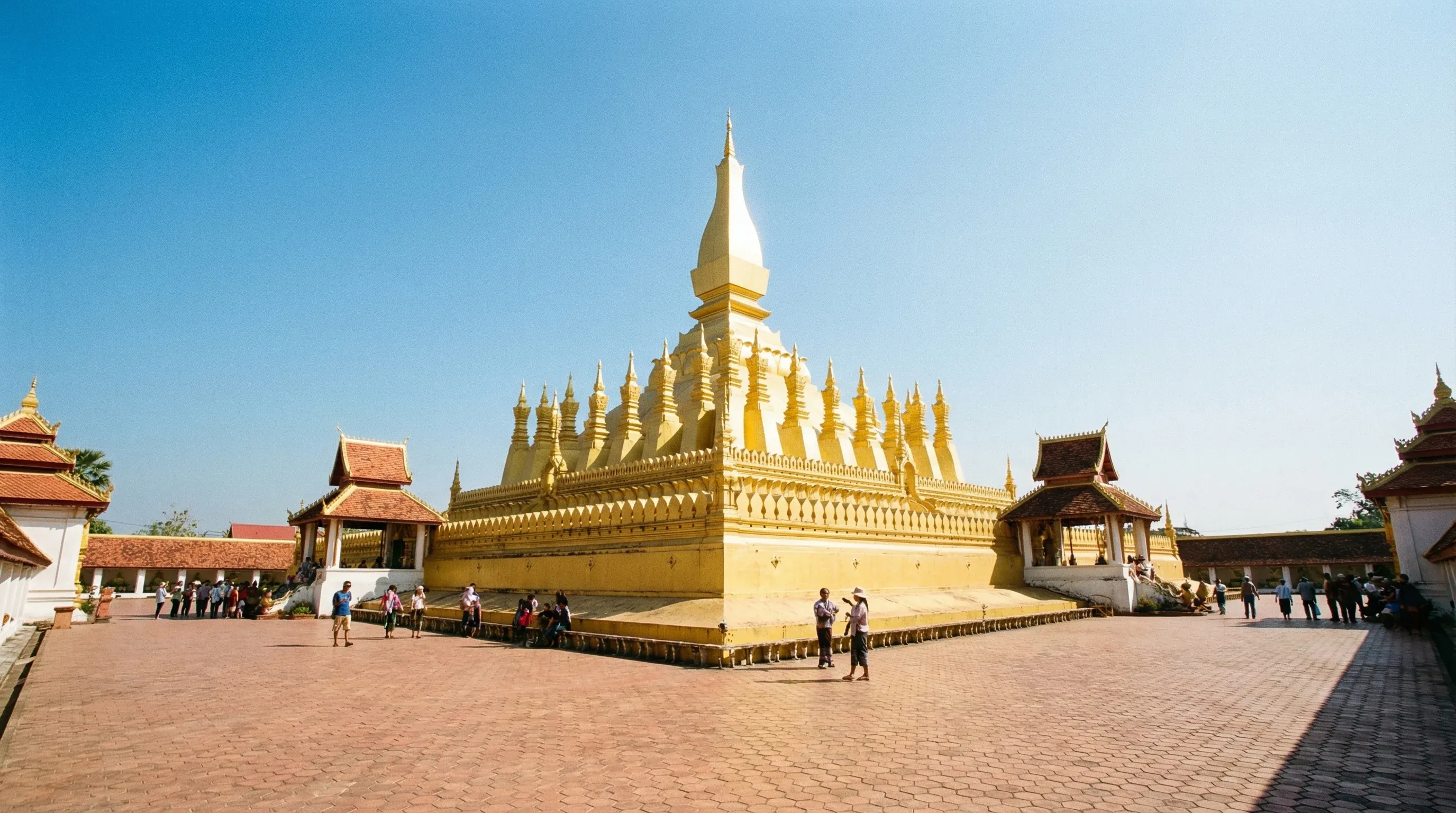 The large golden Pha That Luang stupa in Vientiane under a clear blue sky.