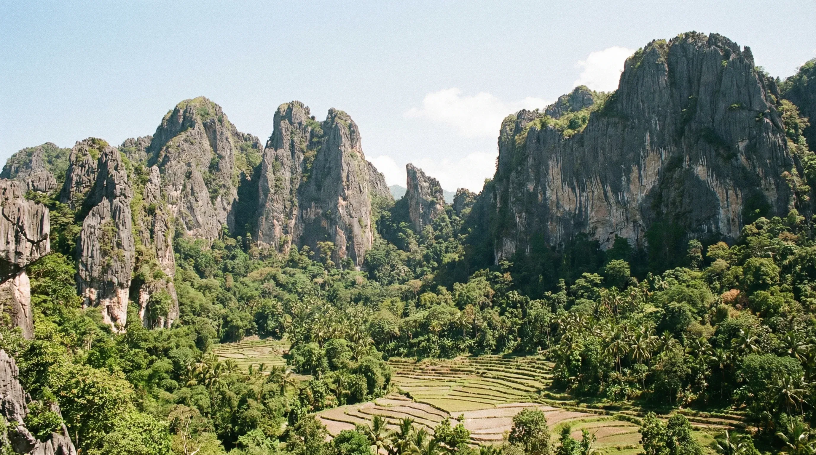 The jagged limestone peaks of Mount Matebian rise above a lush green valley in the eastern mountainous region of Timor-Leste.