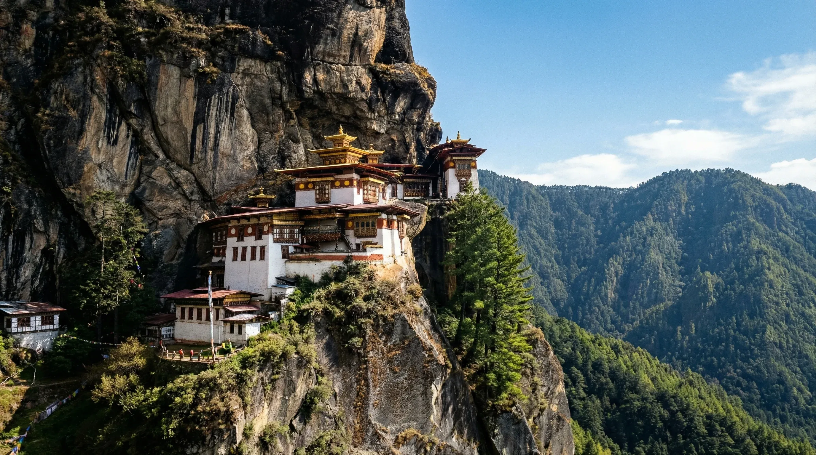 Paro Taktsang monastery built onto a steep cliffside surrounded by pine trees in Bhutan.