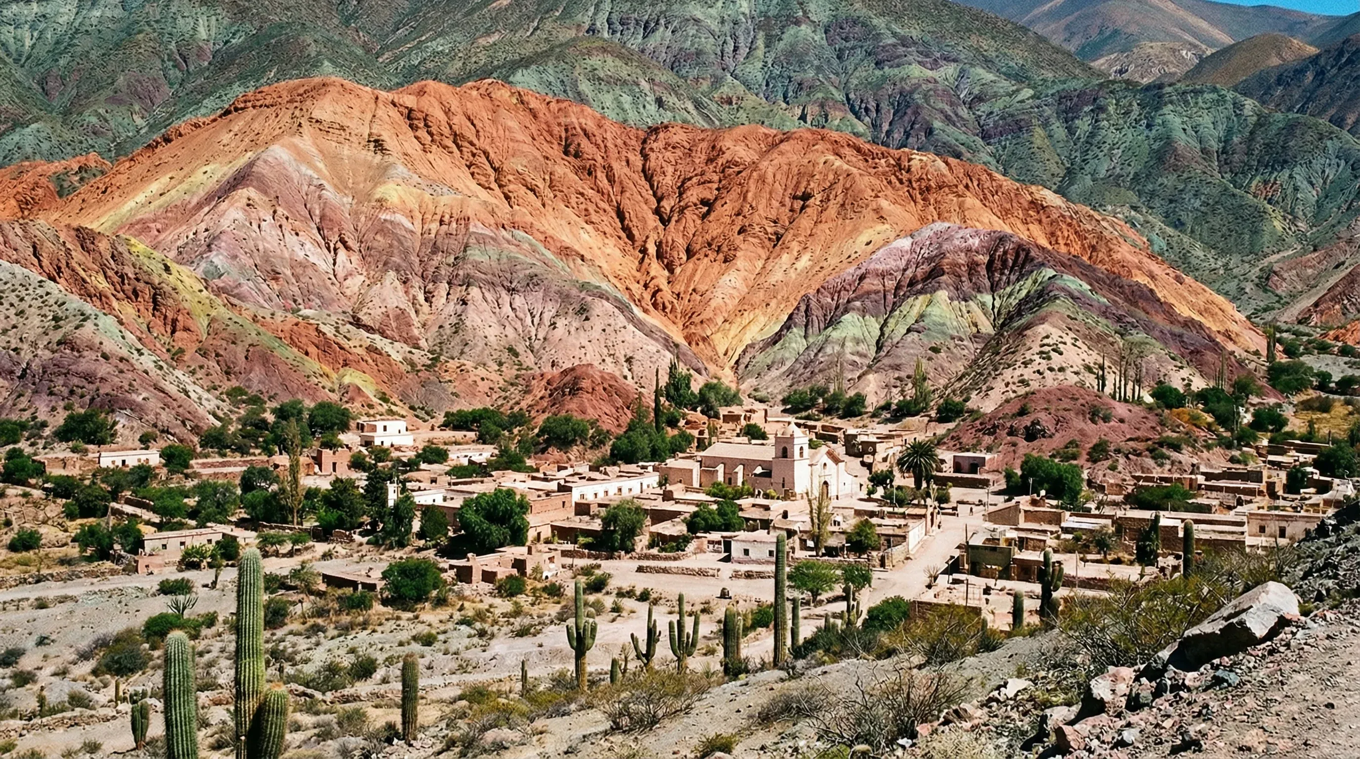 The Hill of Seven Colors in Purmamarca shows layered mineral bands of various colors under a bright sky.