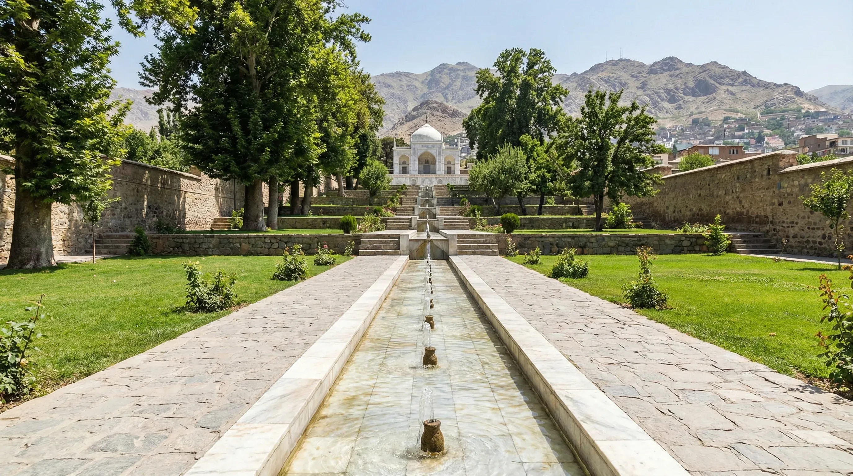 Terraced lawns and a central marble water channel leading toward a white mosque at the Gardens of Babur in Kabul.
