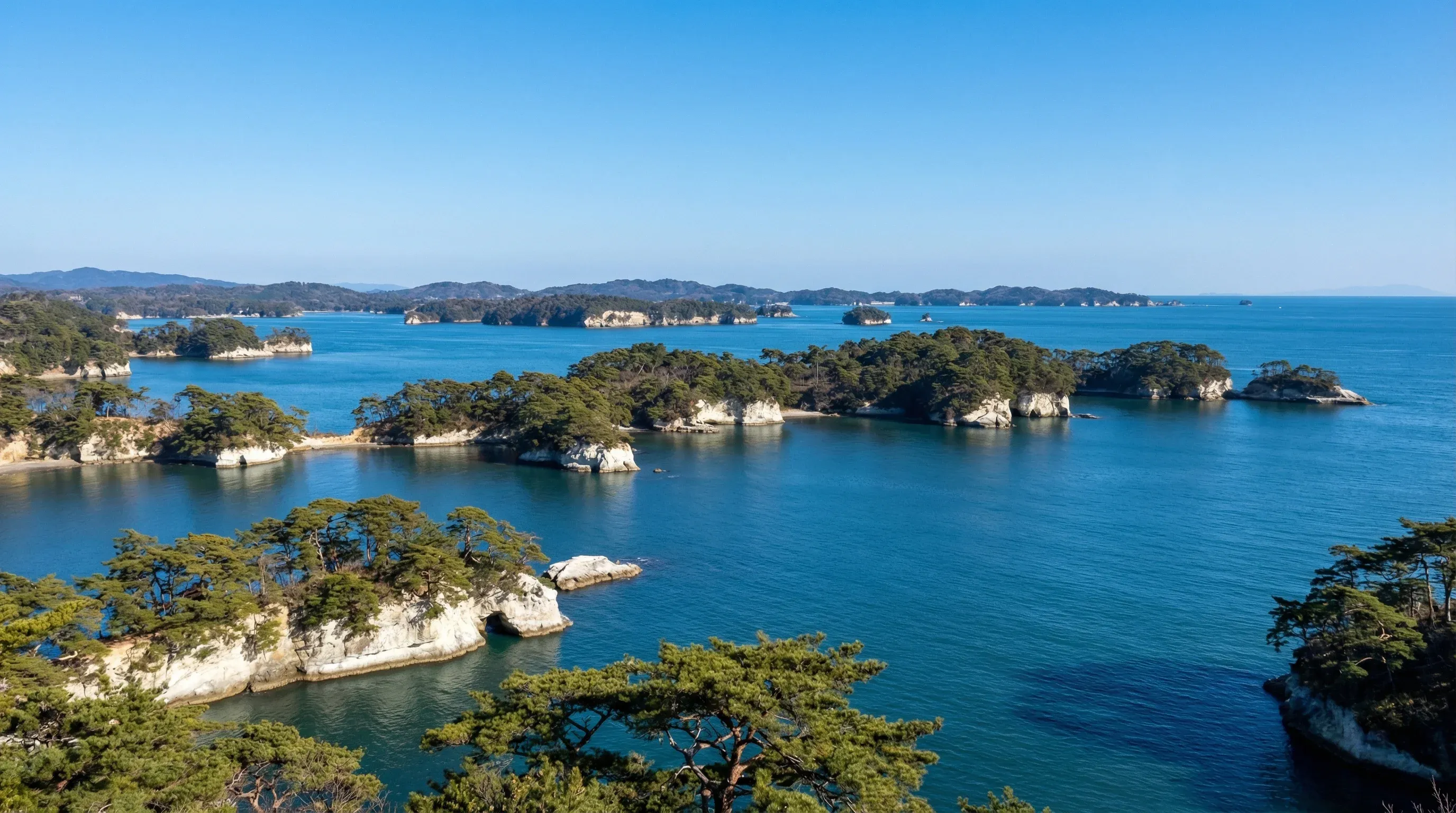 A wide view of the pine-covered islands in the blue waters of Matsushima Bay.
