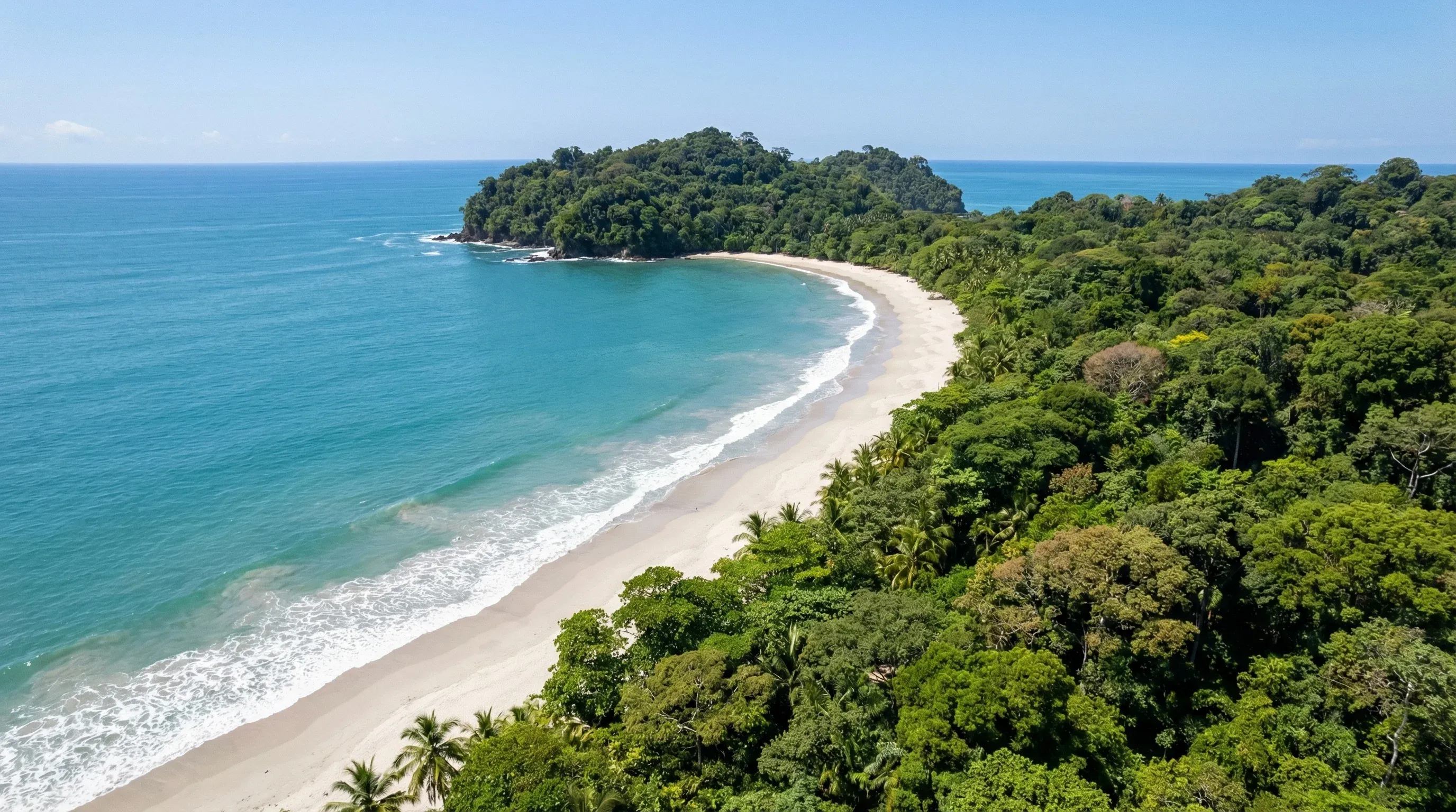 Aerial view of the crescent-shaped white sand beaches and turquoise water of Manuel Antonio National Park.
