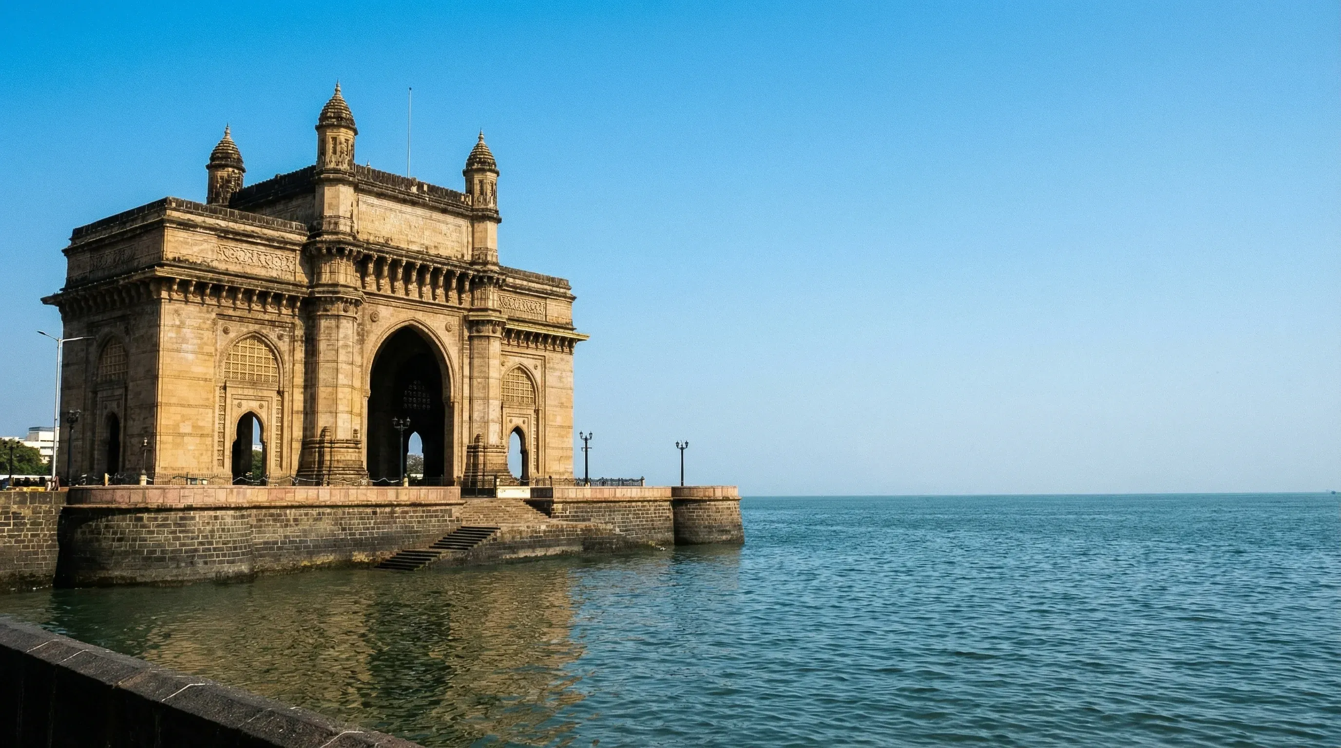 The Gateway of India monument in Mumbai, showing the basalt arch against a clear sky.