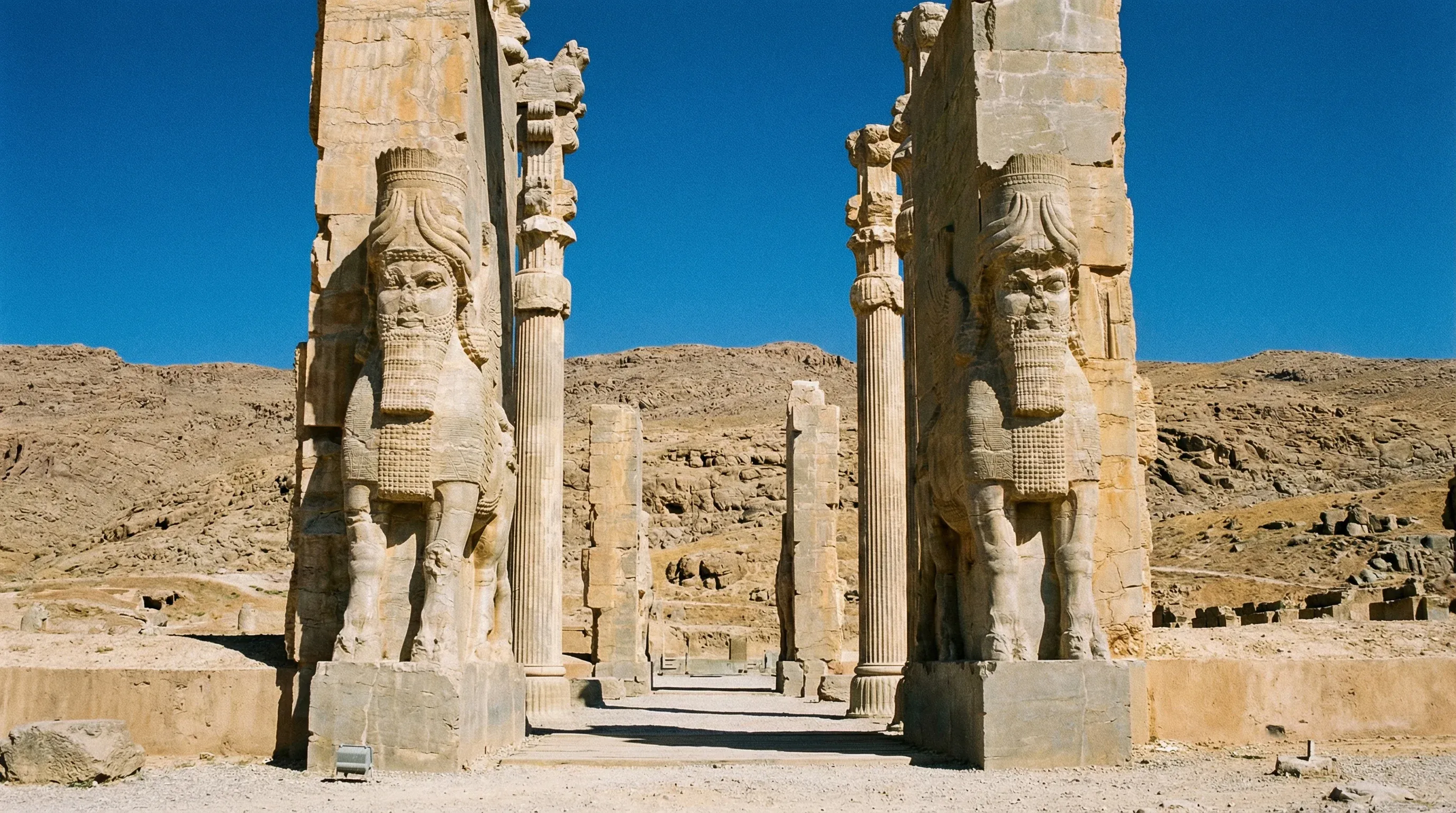 Ancient stone columns and winged bull statues at the Gate of All Nations in the ruins of Persepolis.