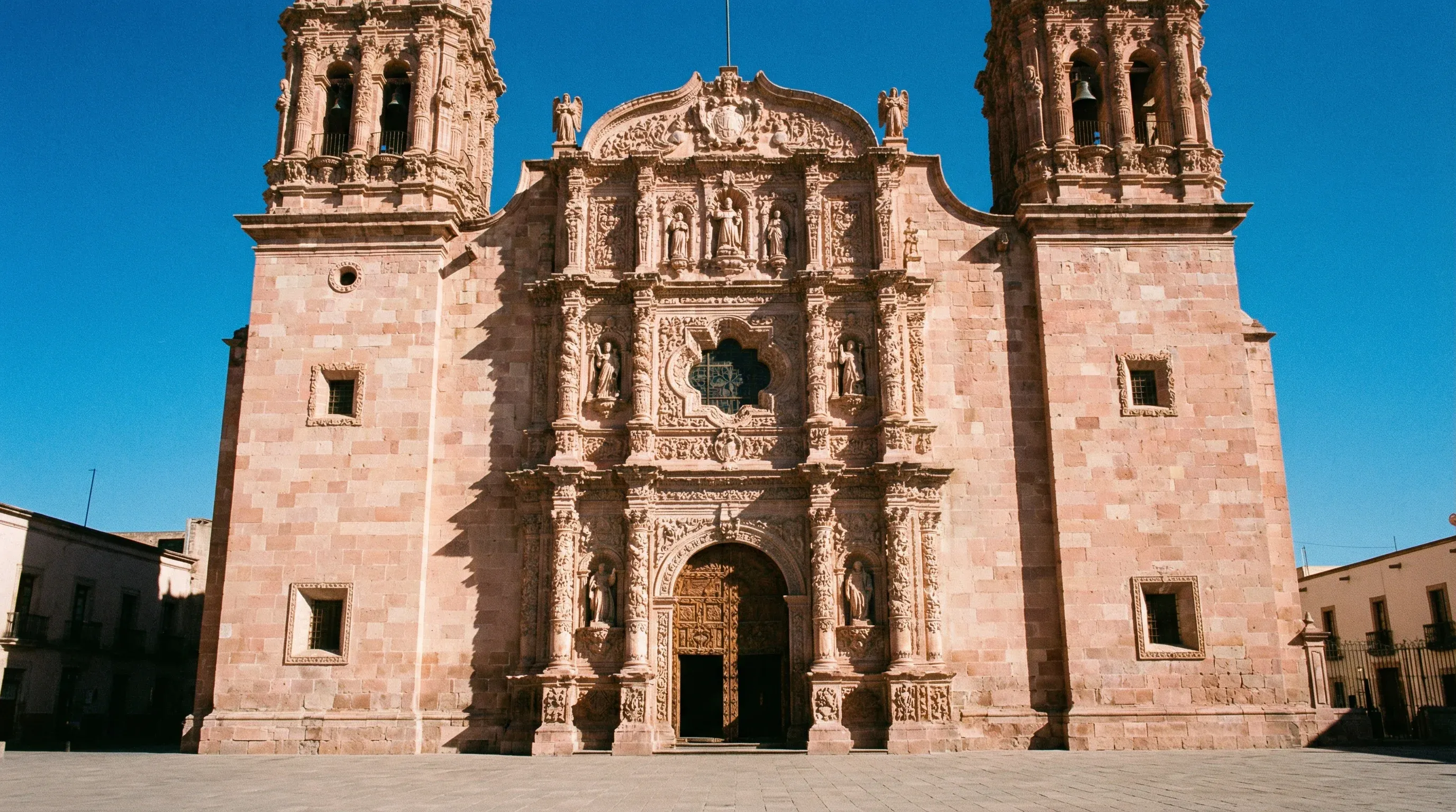 The intricate pink sandstone facade and twin towers of the Zacatecas Cathedral under a bright, clear sky.