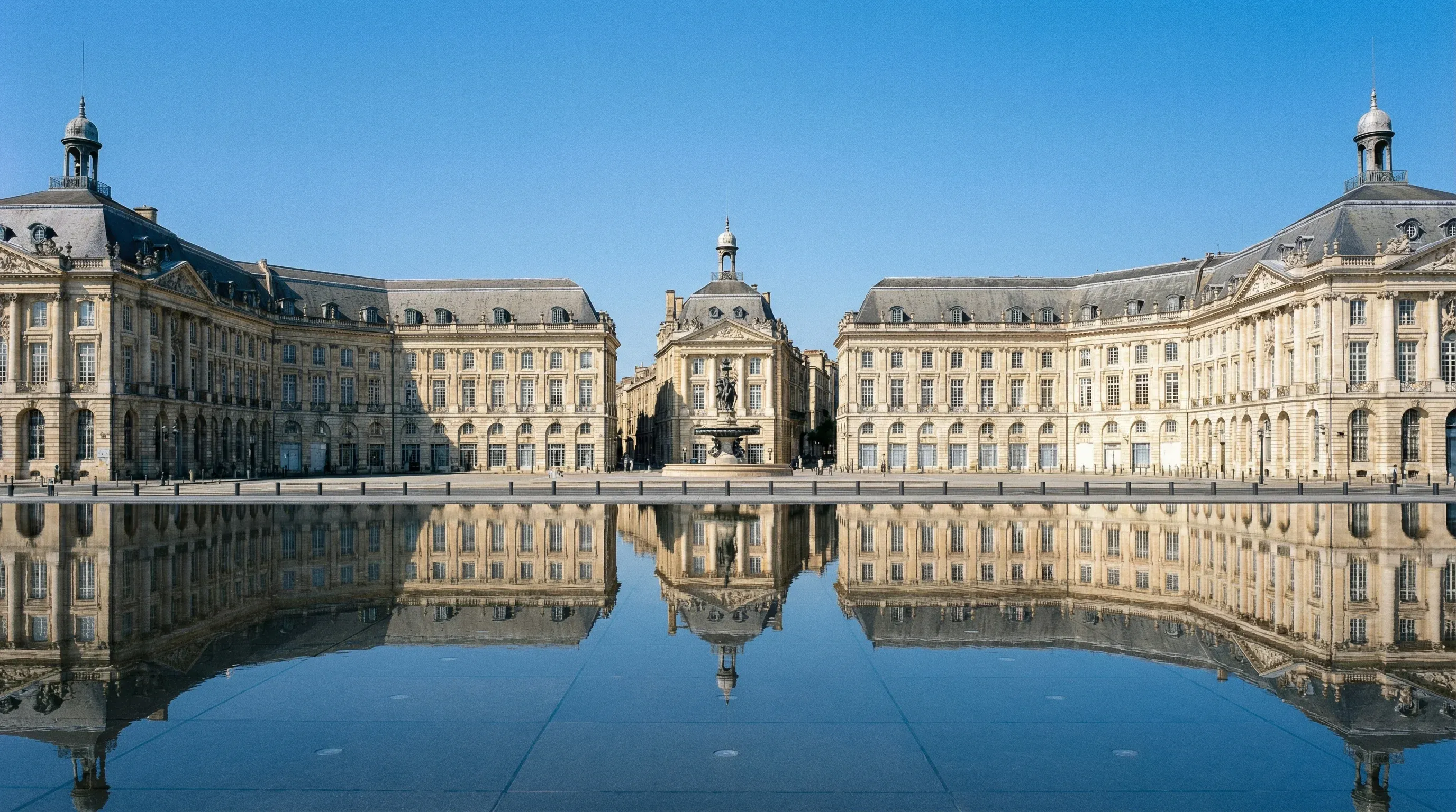 The 18th-century limestone buildings of the Place de la Bourse reflected in the Water Mirror plaza in Bordeaux, France.