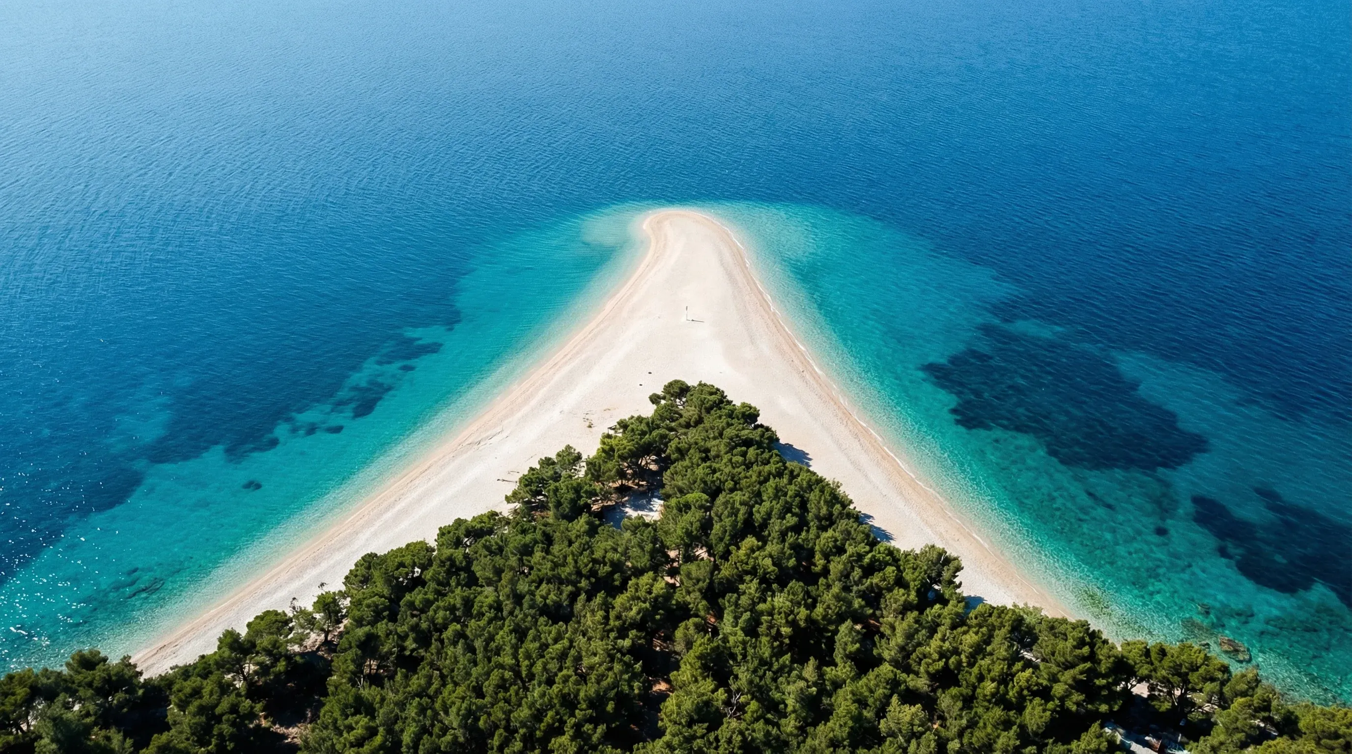 Aerial view of Zlatni Rat beach, a distinctive white pebble spit extending into the turquoise Adriatic Sea on Brač island.