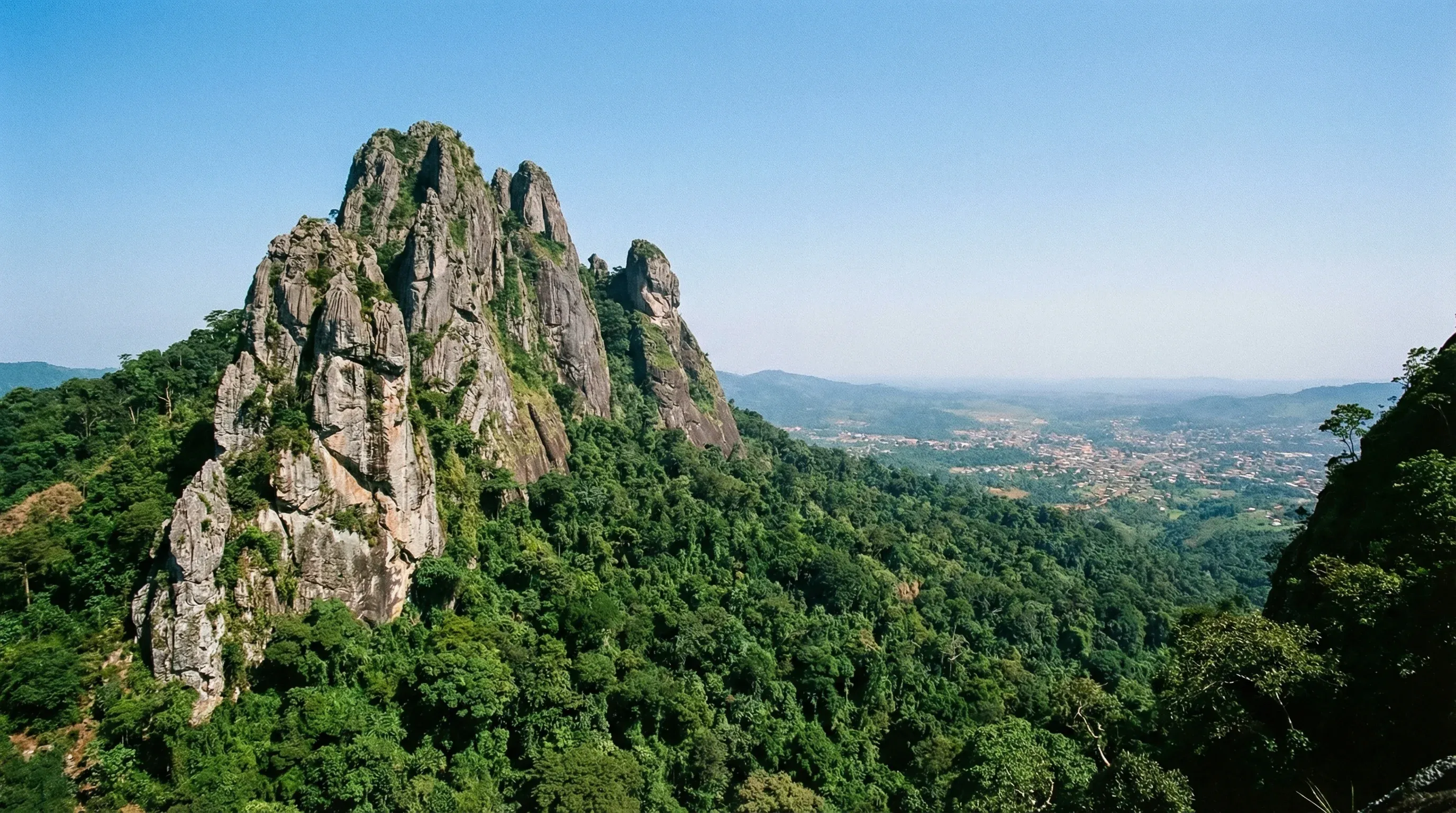 The rocky Dent de Man mountain peak rising above the dense green tropical forests of the western highlands.