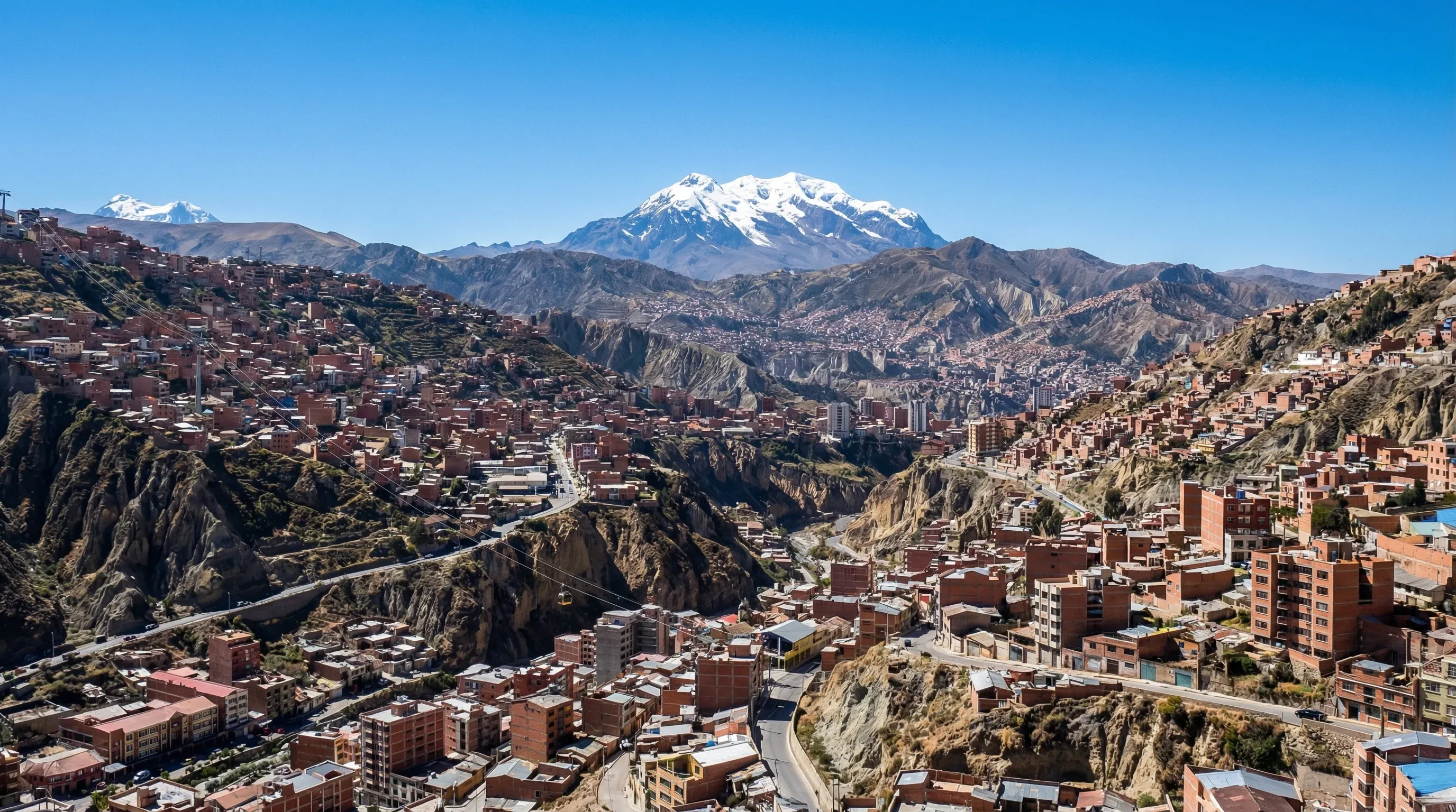 A sprawling city built into a high-altitude valley with a massive snow-covered mountain peak in the background.