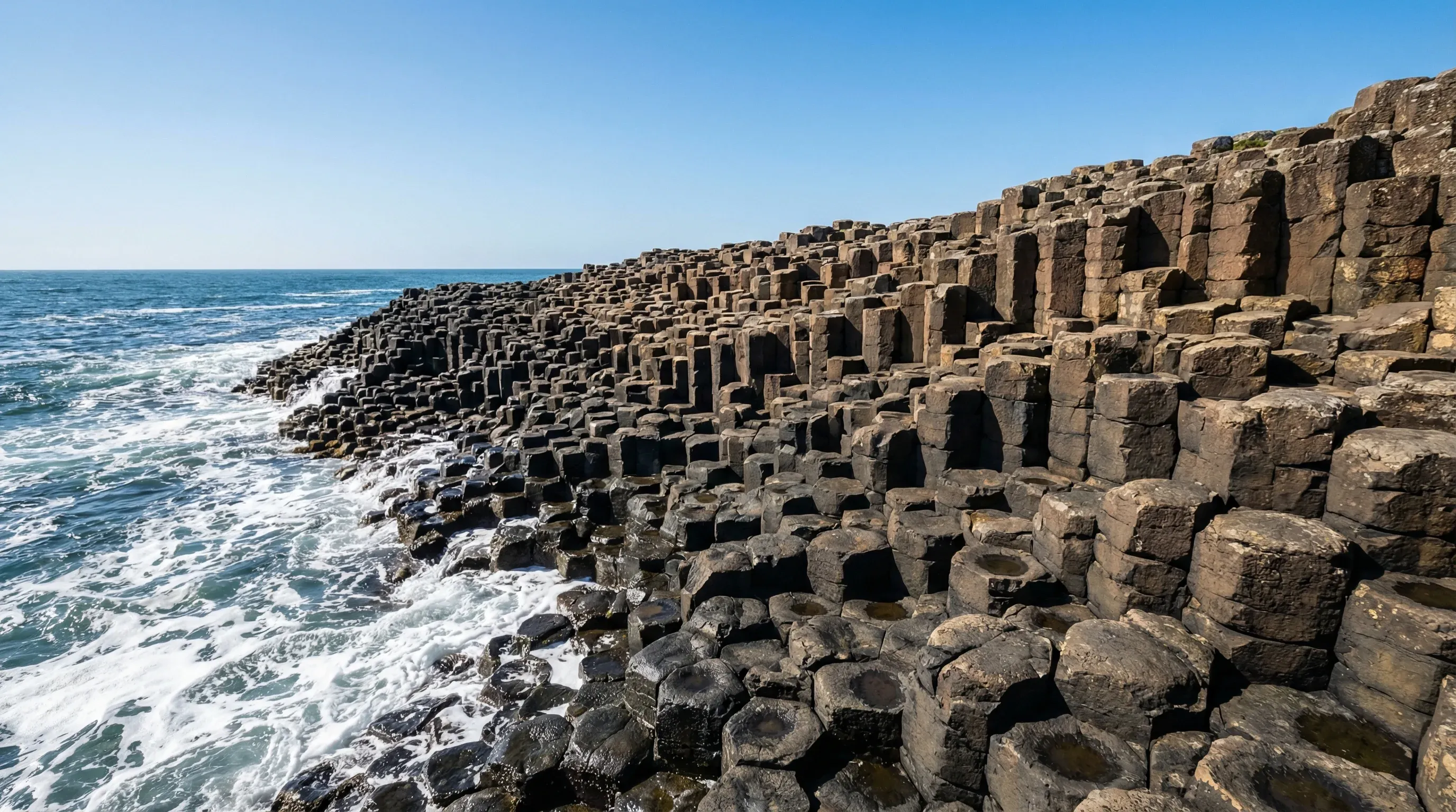 Geometric basalt stone columns leading into the sea at the Giant's Causeway on the coast of Northern Ireland.