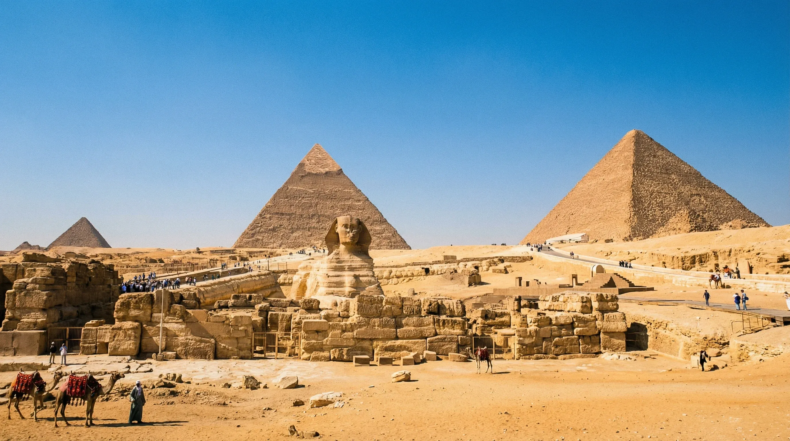 The three main Giza pyramids and the Great Sphinx on a desert plateau under a clear blue sky.