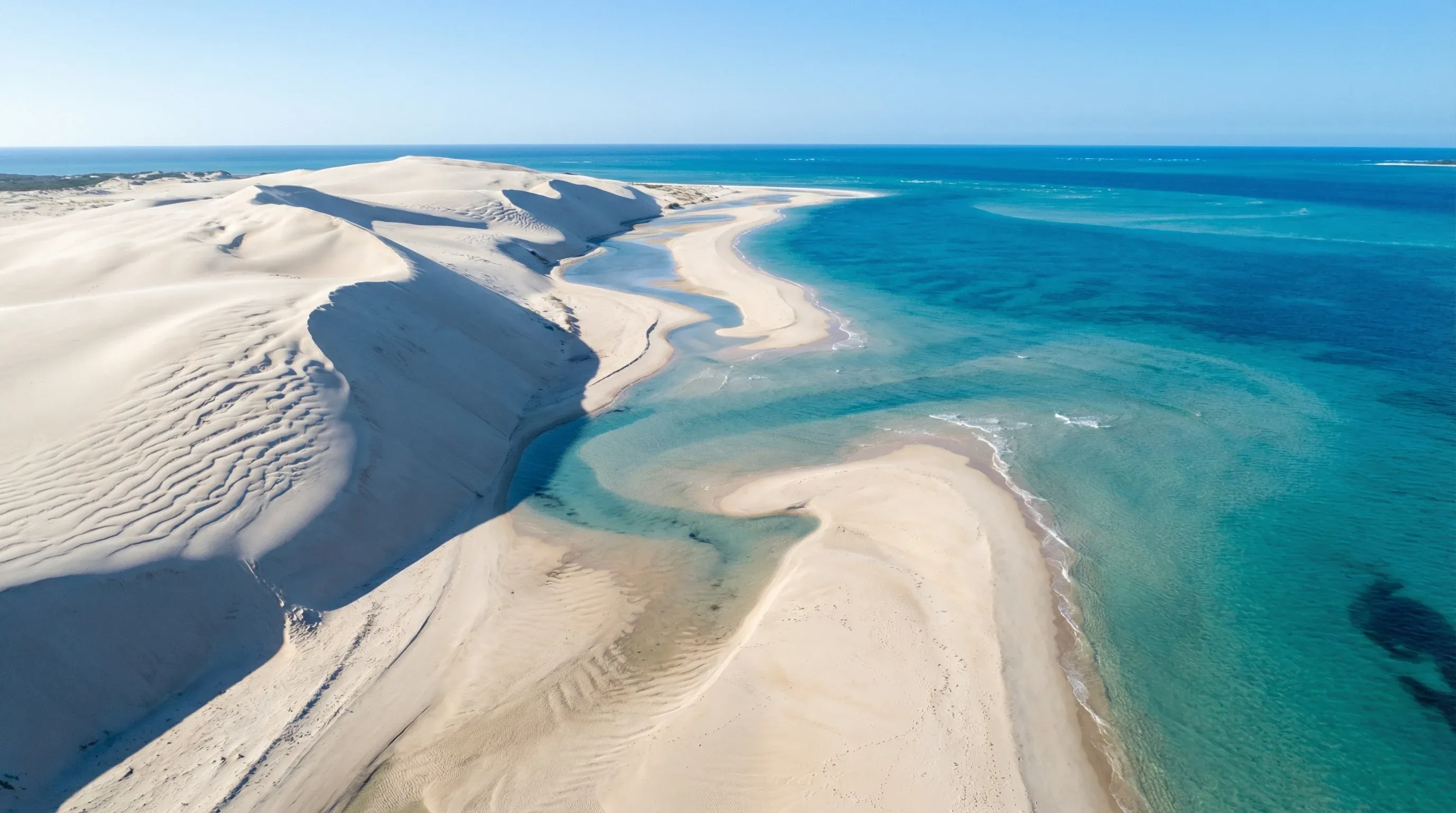 Aerial view of high white sand dunes meeting turquoise ocean waters at Bazaruto Island, Mozambique.