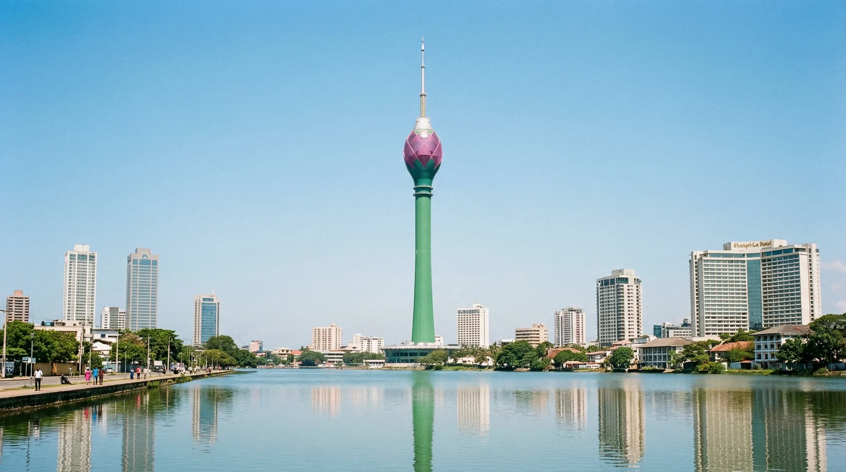 The Lotus Tower rises above the Colombo skyline and Beira Lake under a clear blue sky in Sri Lanka.