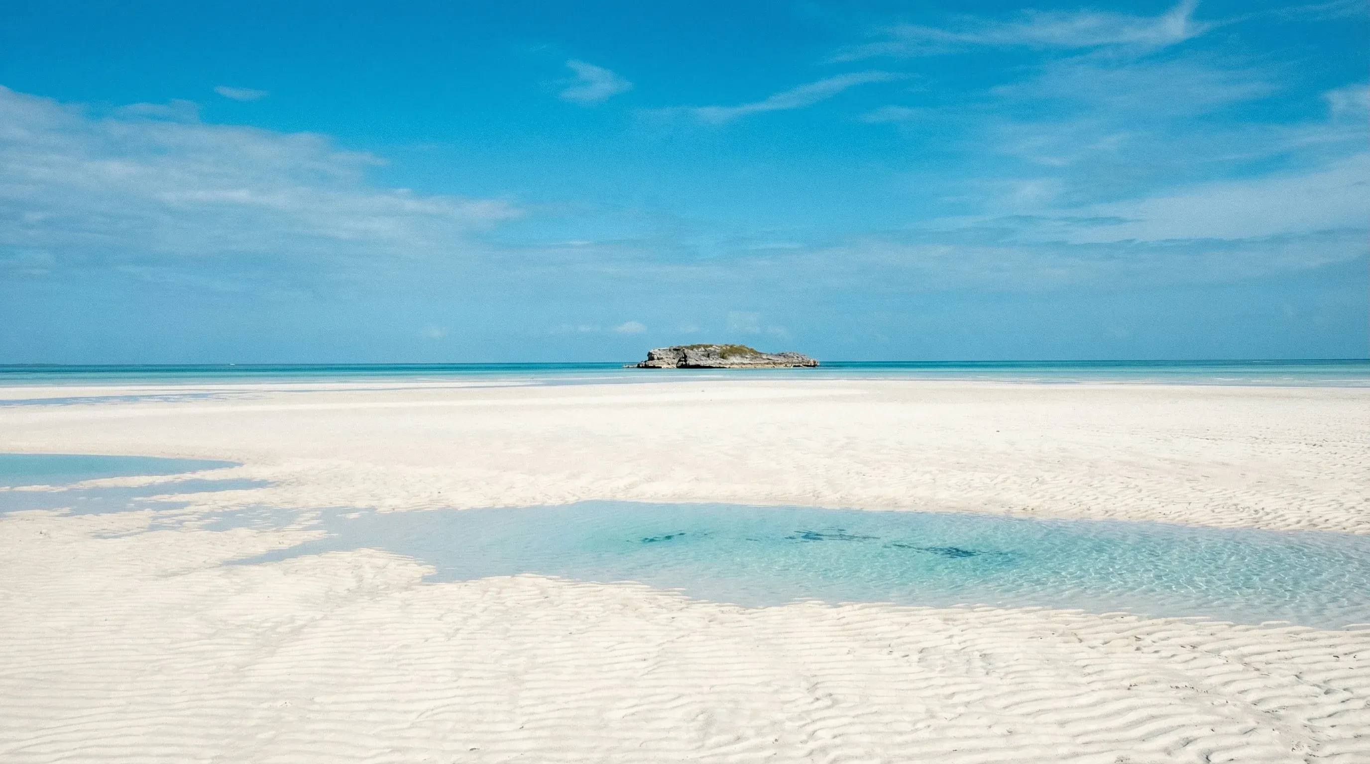 Wide rippled sand flats and shallow turquoise water at Gold Rock Beach in Grand Bahama at low tide.