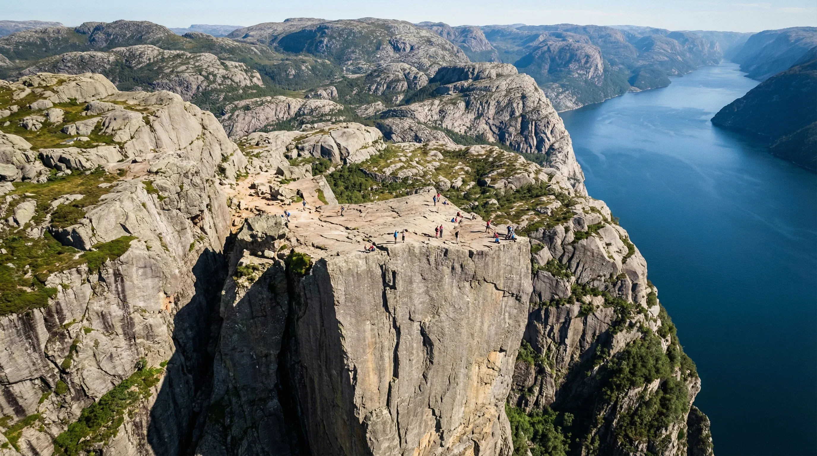 The flat-topped Preikestolen cliff overlooking the deep blue Lysefjord and surrounding rocky mountains.