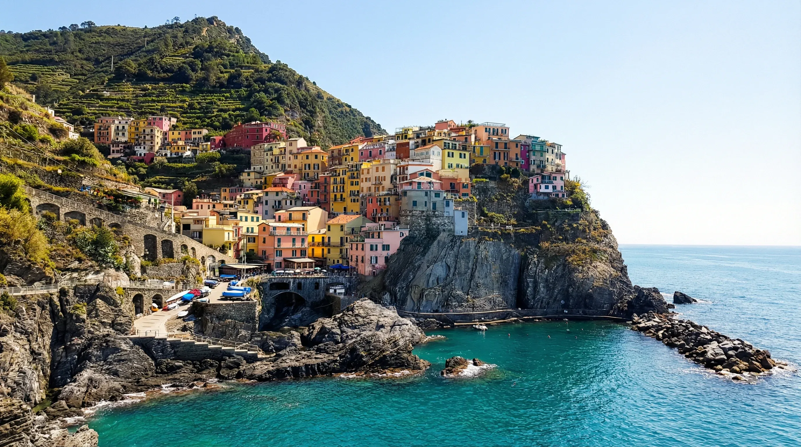 Pastel-colored houses of Manarola village built onto a rocky cliffside overlooking the blue Ligurian Sea.