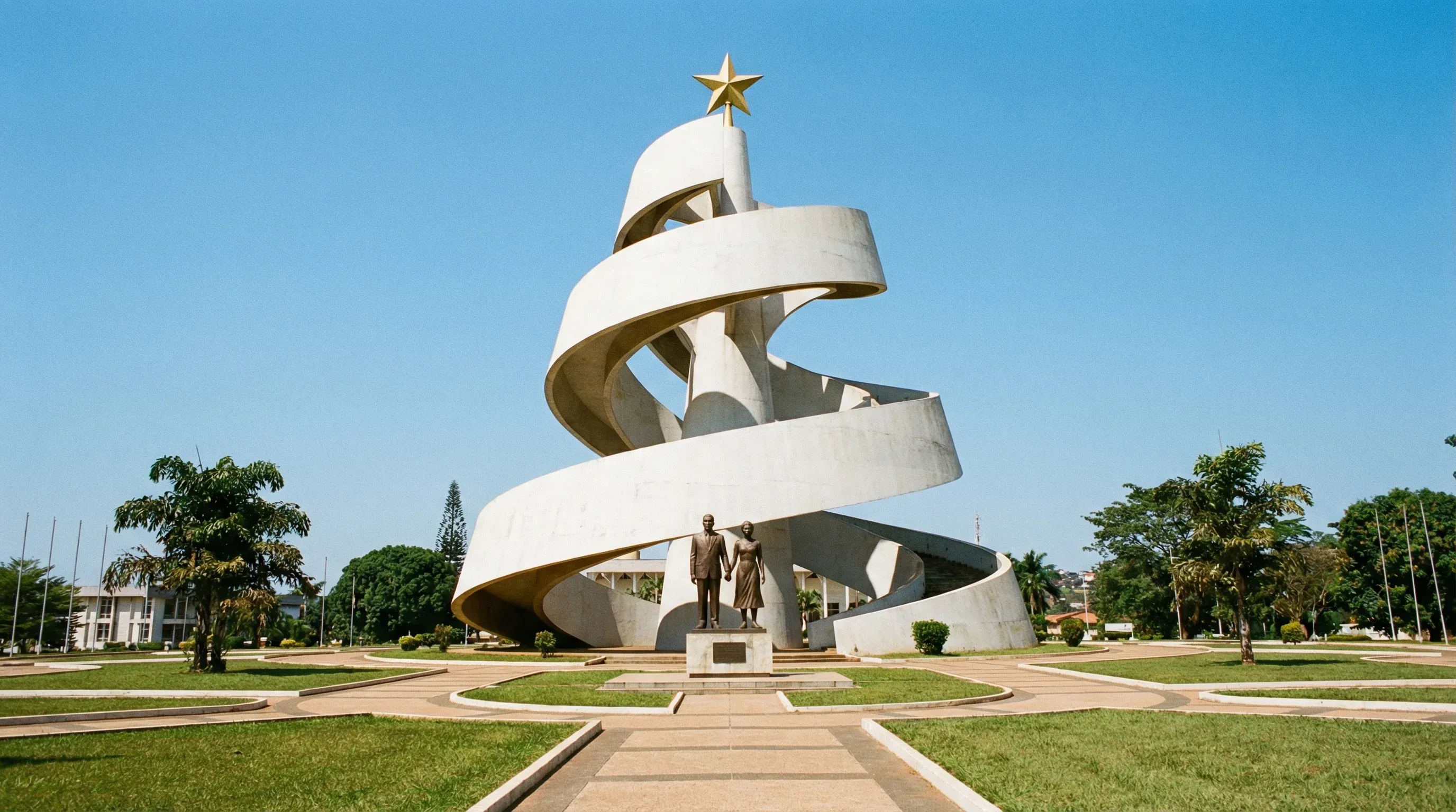 The spiral white concrete Reunification Monument and bronze sculpture in a landscaped park in Yaoundé.