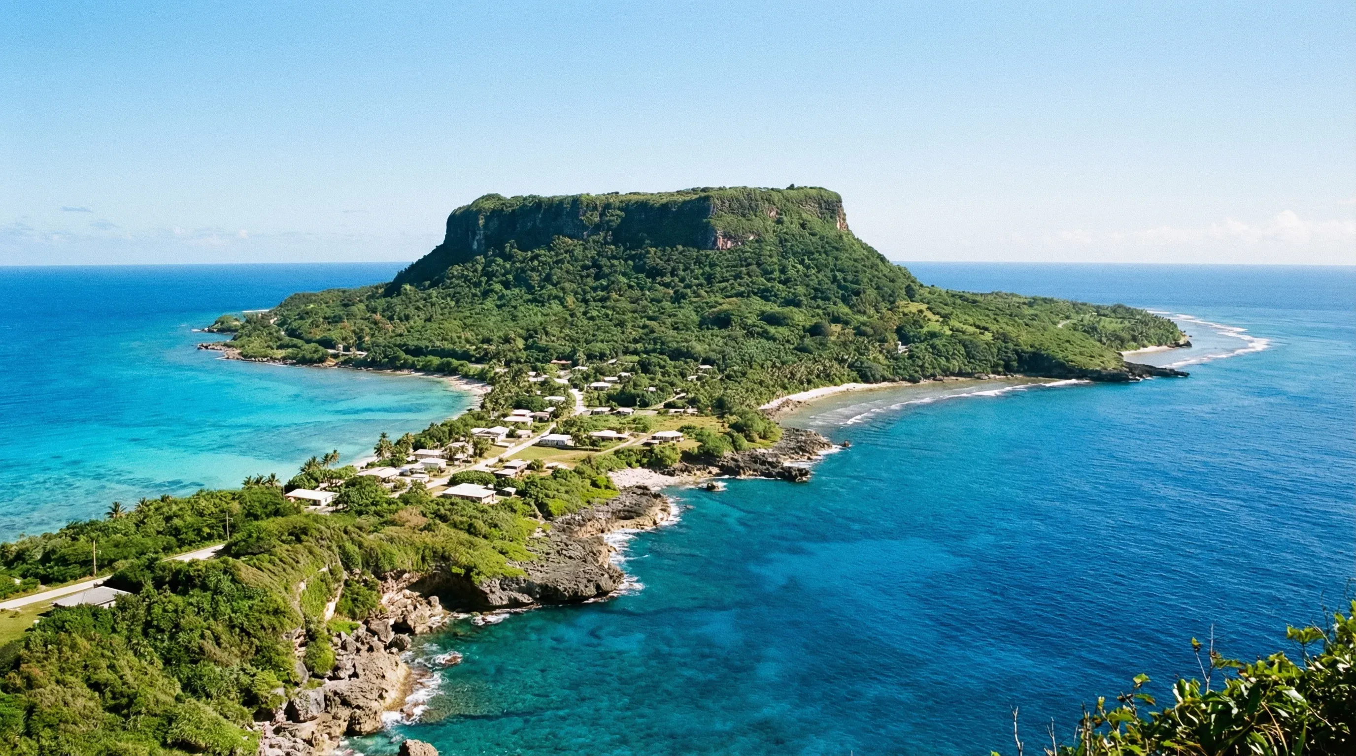 A wide-angle view of the layered Wedding Cake Mountain rising above the narrow isthmus and coastline of Rota.