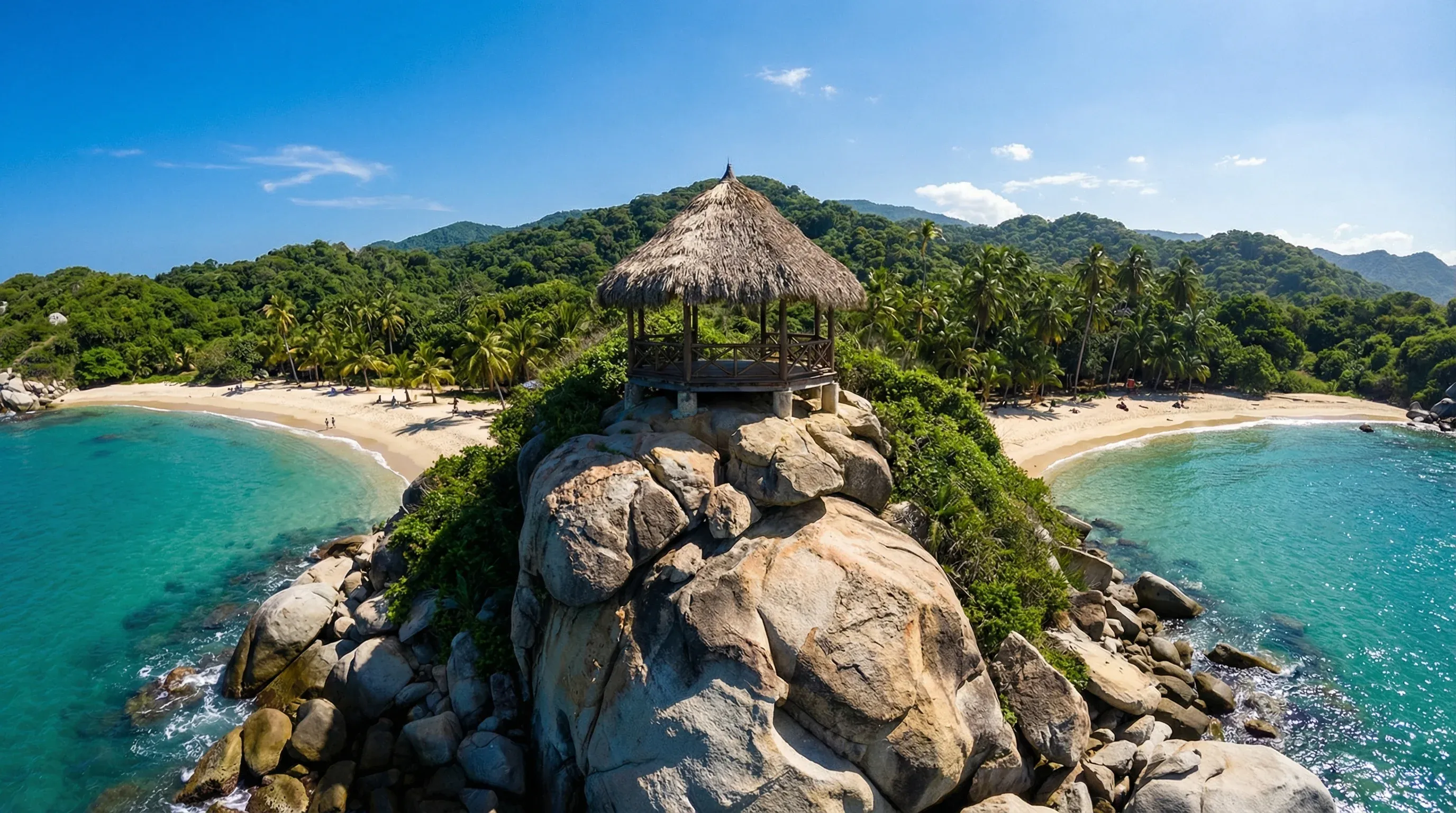 A thatched-roof hut on a rocky point between two sandy bays and turquoise water in Tayrona National Park.