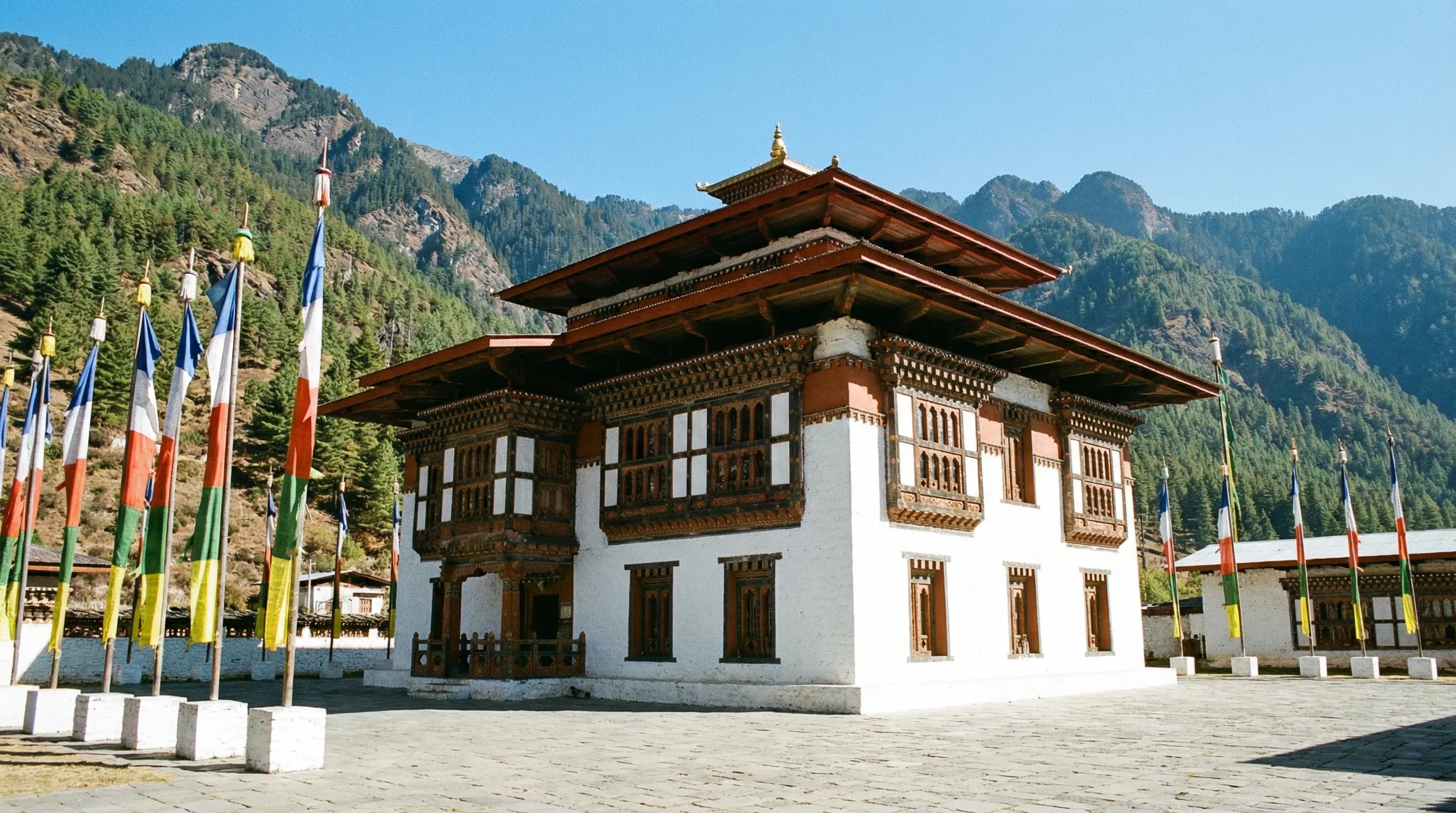 The white-walled Lhakhang Karpo temple situated against a backdrop of forested mountains in the Haa Valley.