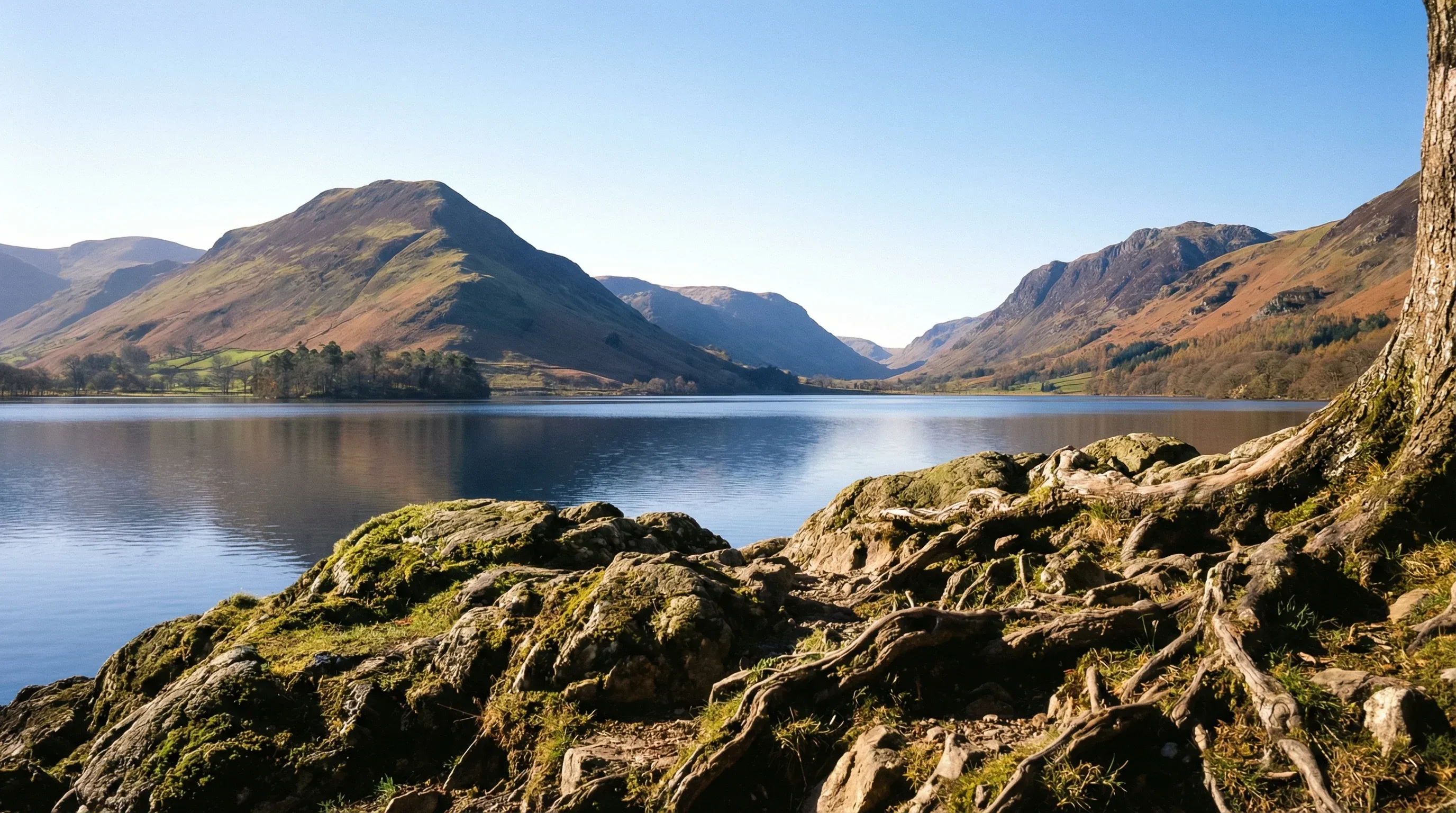 The water of Derwentwater lake surrounded by green hills in the Lake District, England, on a clear day.