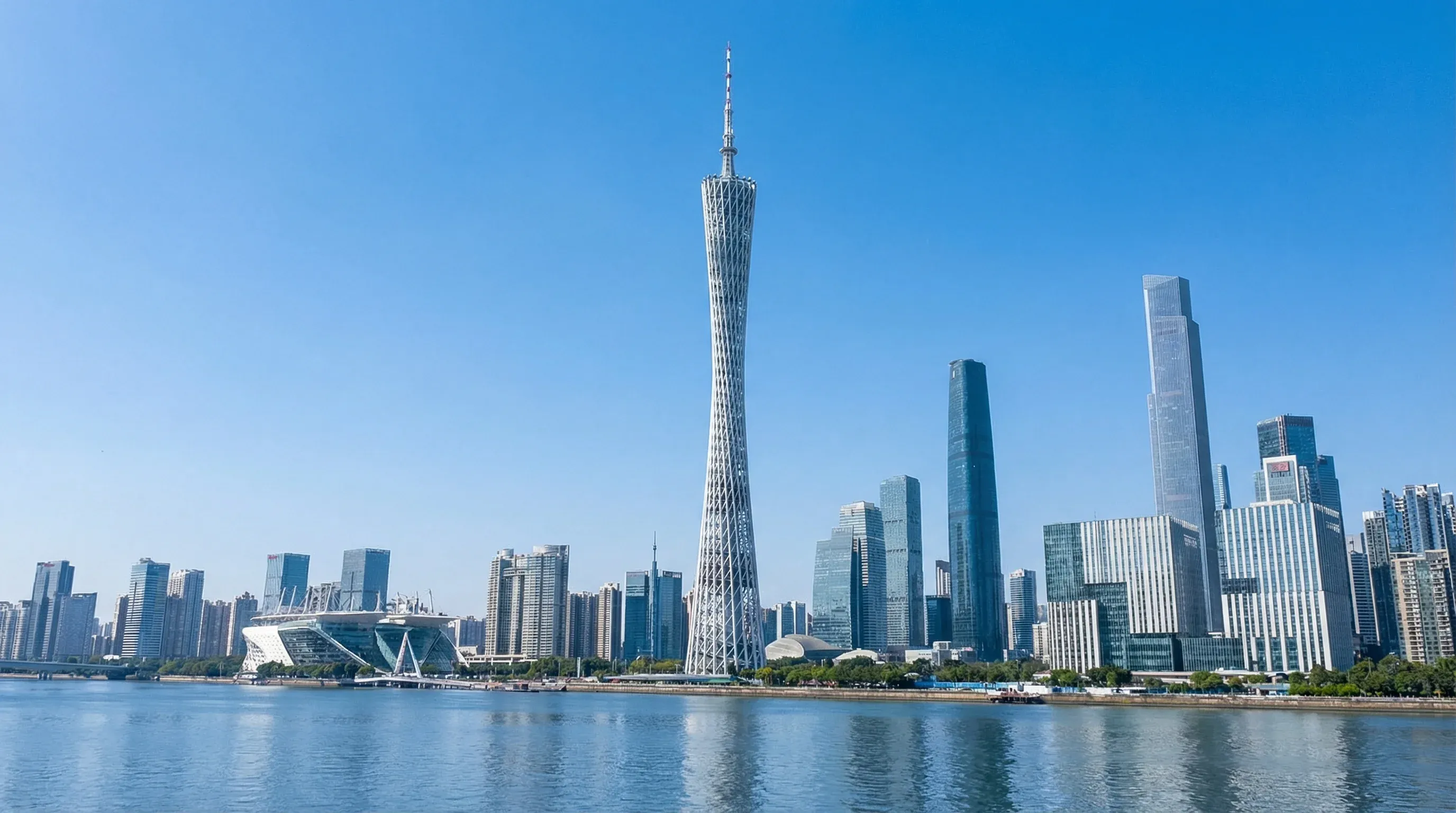 The tall, twisting Canton Tower standing next to the Pearl River under a bright midday sky.