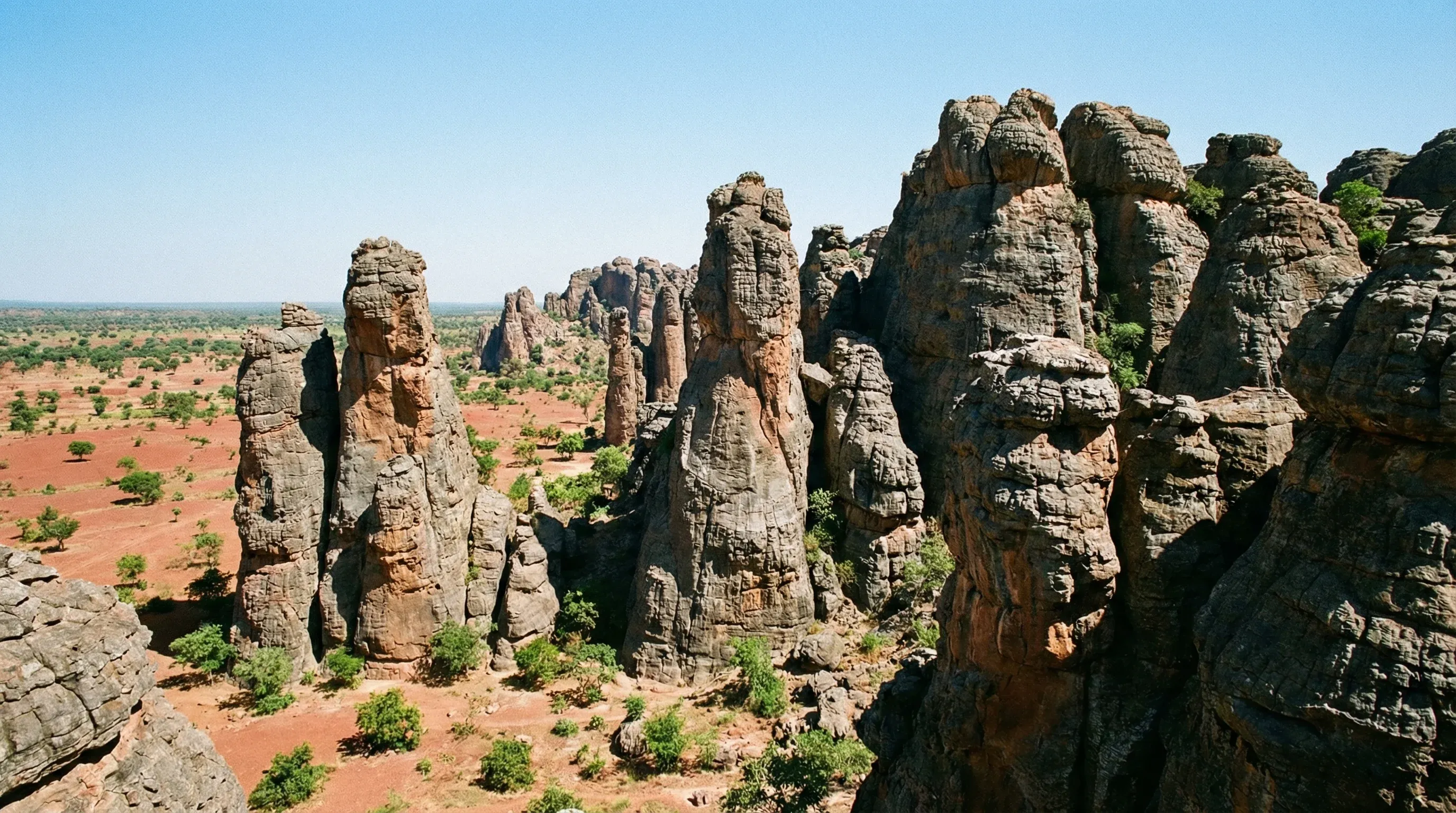 Sharp, vertical sandstone rock formations known as the Sindou Peaks rising from the savannah in southwestern Burkina Faso under a midday sun.
