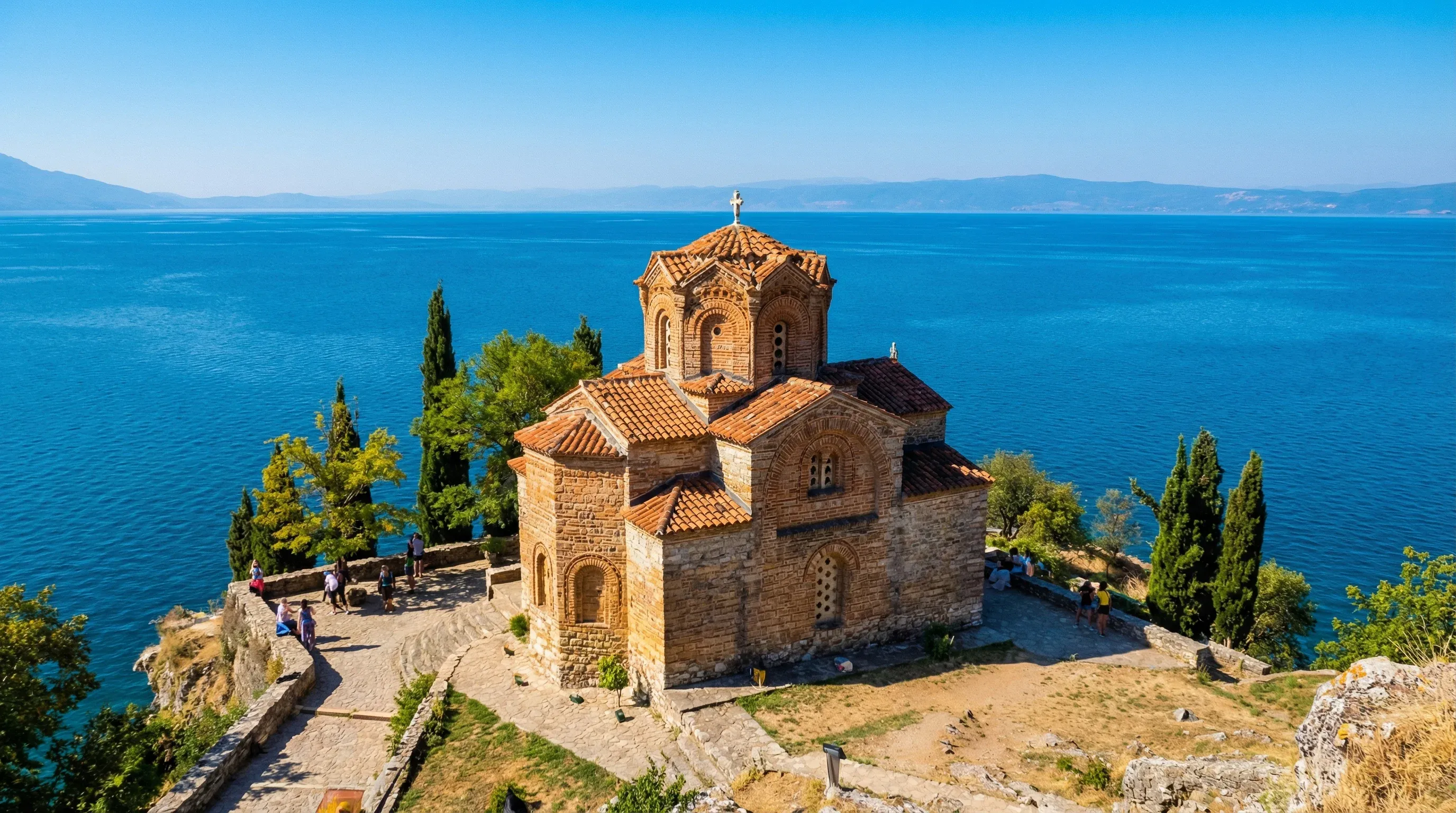 The medieval brick Church of Saint John at Kaneo on a rocky cliff overlooking the blue water of Lake Ohrid.