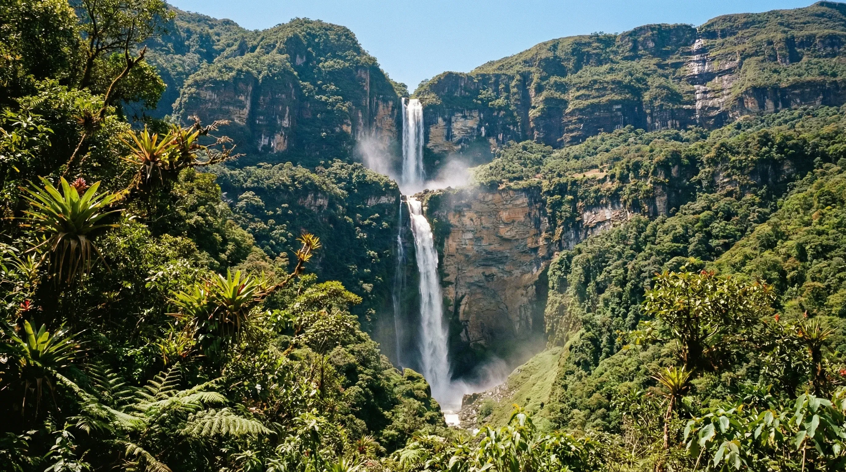A tall two-tiered waterfall cascading down a green forested cliff into a valley in northern Peru.