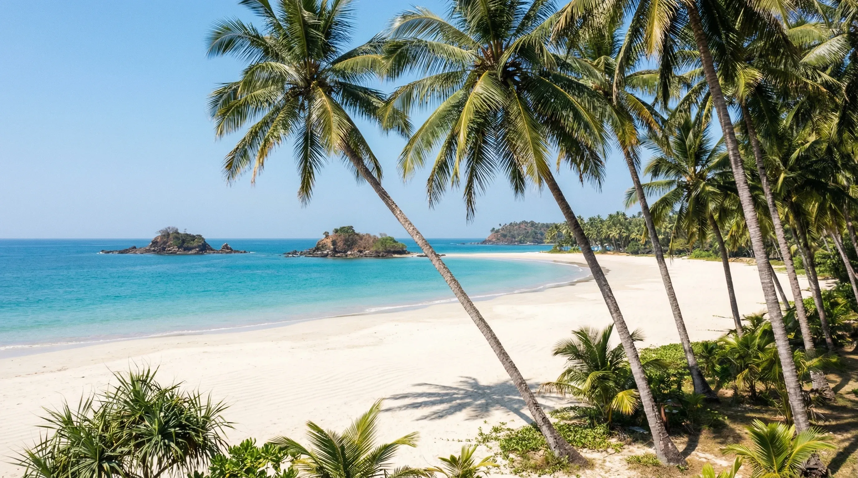 A white sand beach with leaning palm trees and turquoise water at Ngapali Beach.