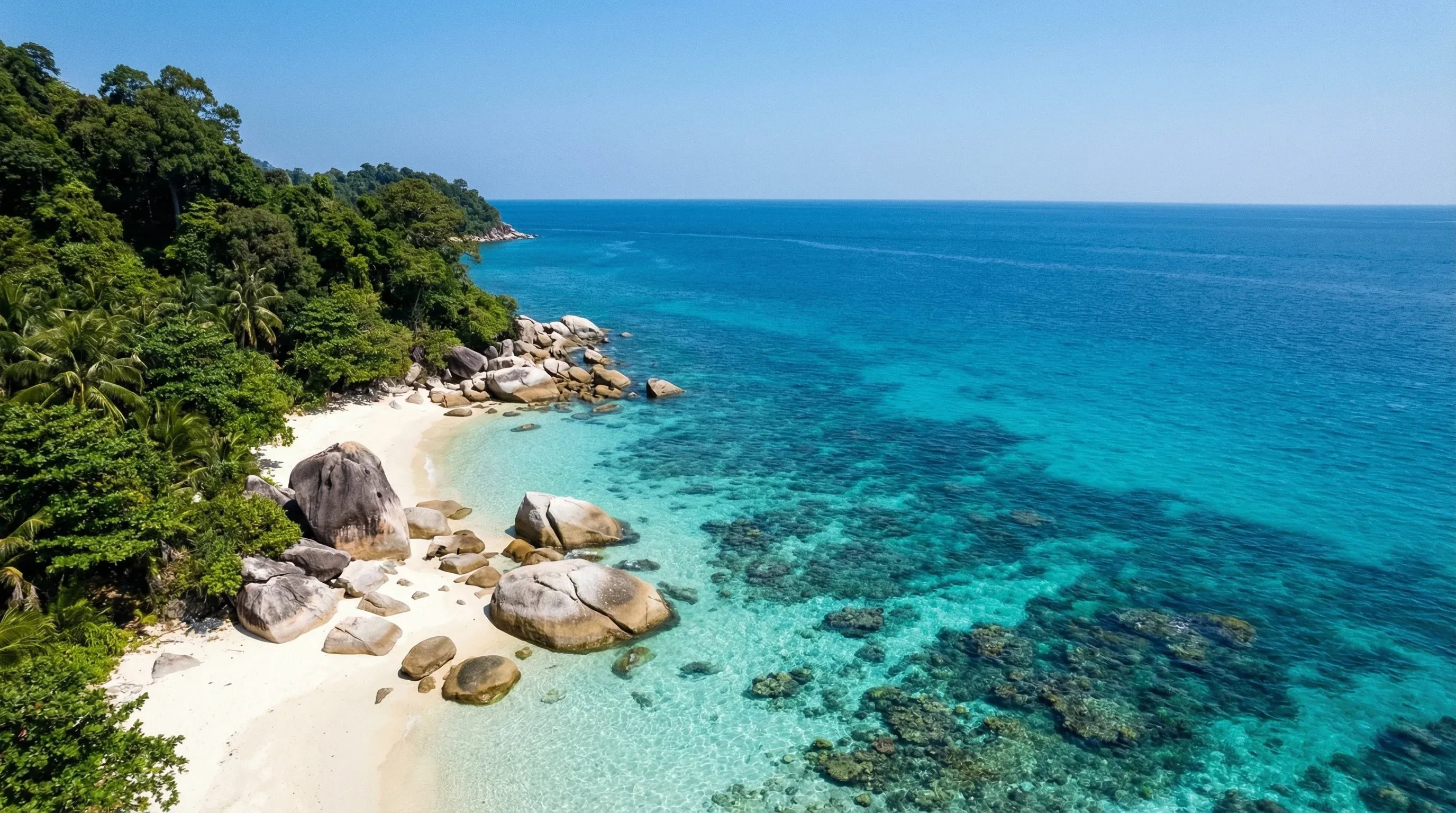 Crystal-clear turquoise water and white sandy beaches with granite rocks and tropical jungle in the Perhentian Islands.