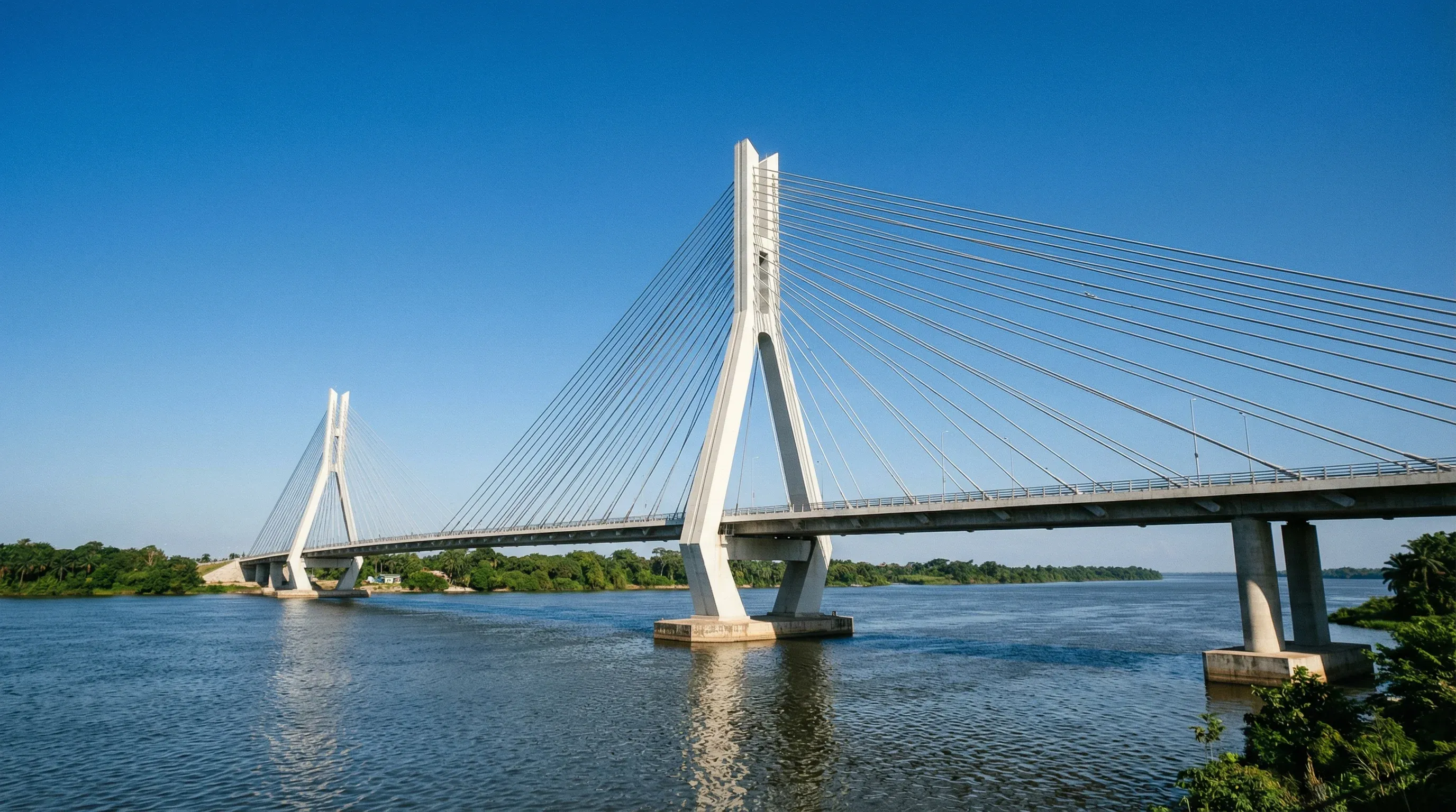 A modern white cable-stayed bridge spanning the landscape in Brazzaville under a clear blue sky.