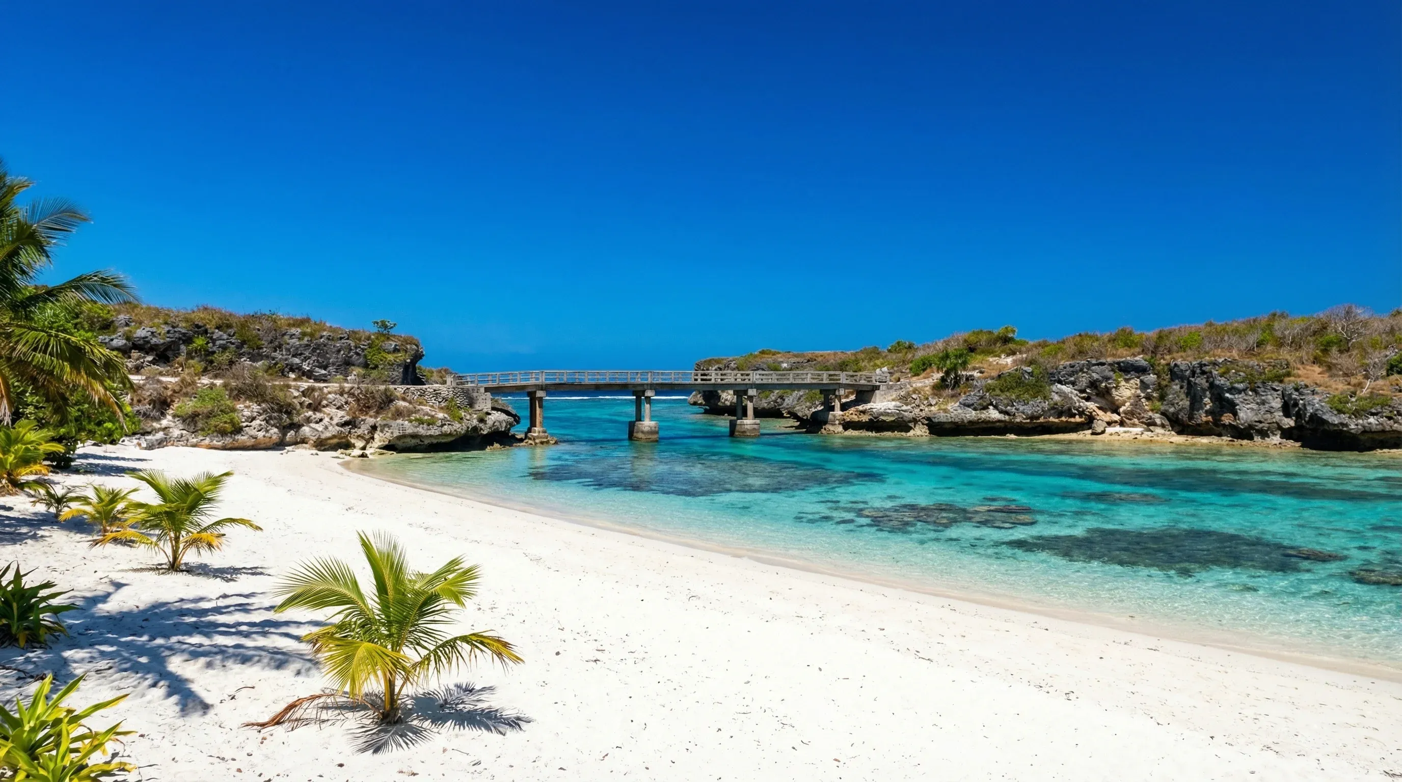 The white sand Mouli Beach and its iconic bridge overlooking the turquoise lagoon of Ouvéa in the Loyalty Islands.
