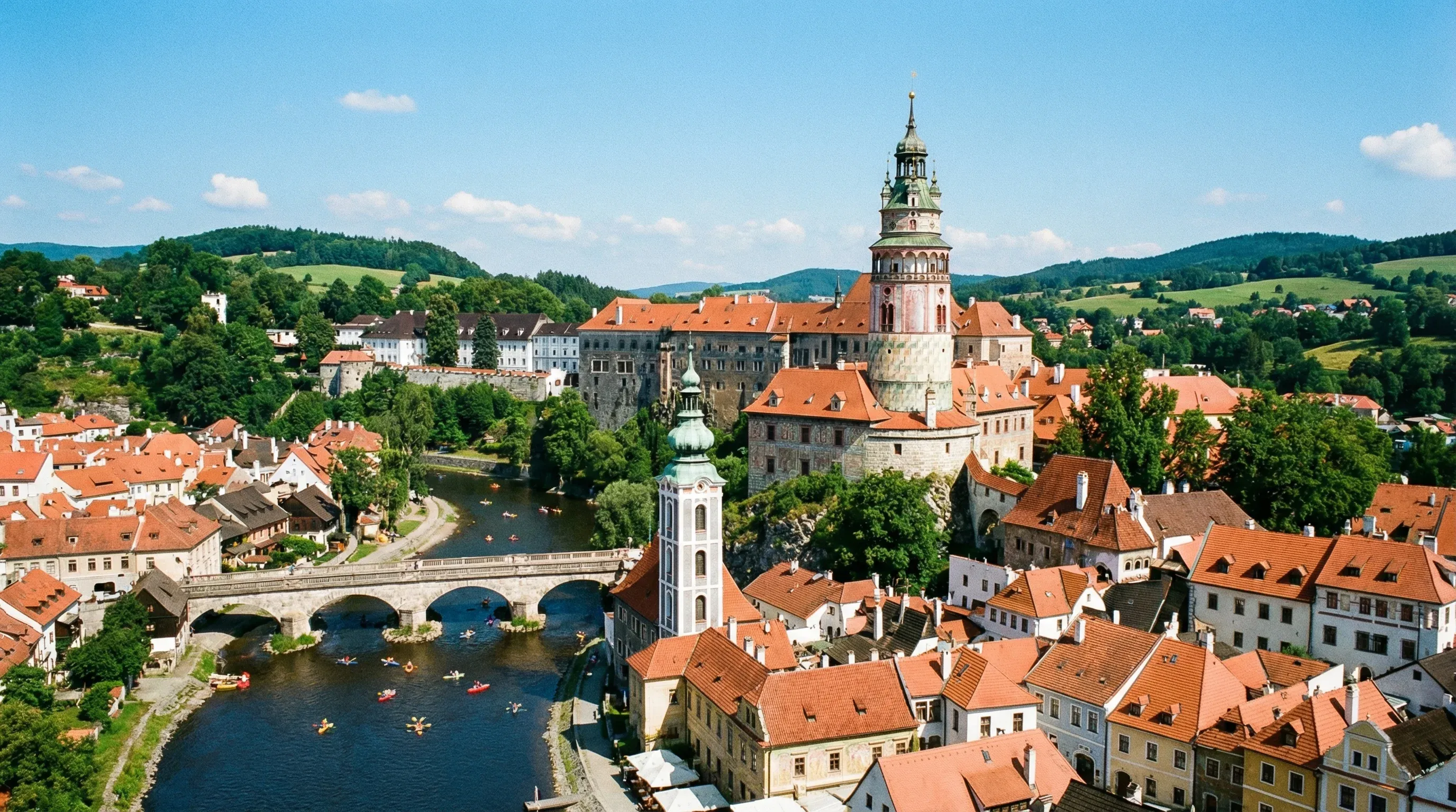 A high-angle view of the colourful Renaissance castle tower and historic red-tiled roofs of Český Krumlov.