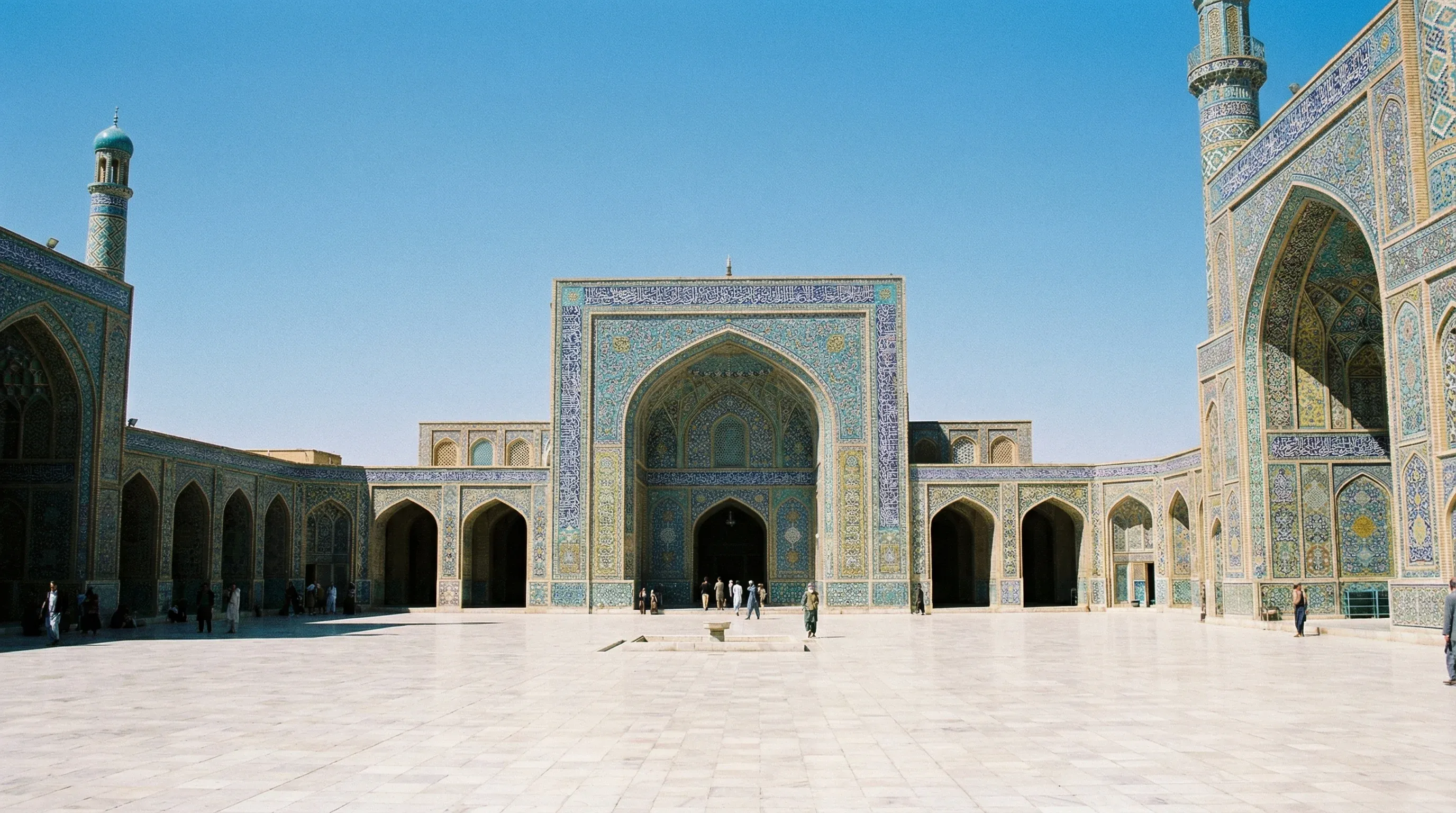 The tiled facade and grand courtyard of the Great Mosque of Herat, featuring intricate blue mosaic patterns.