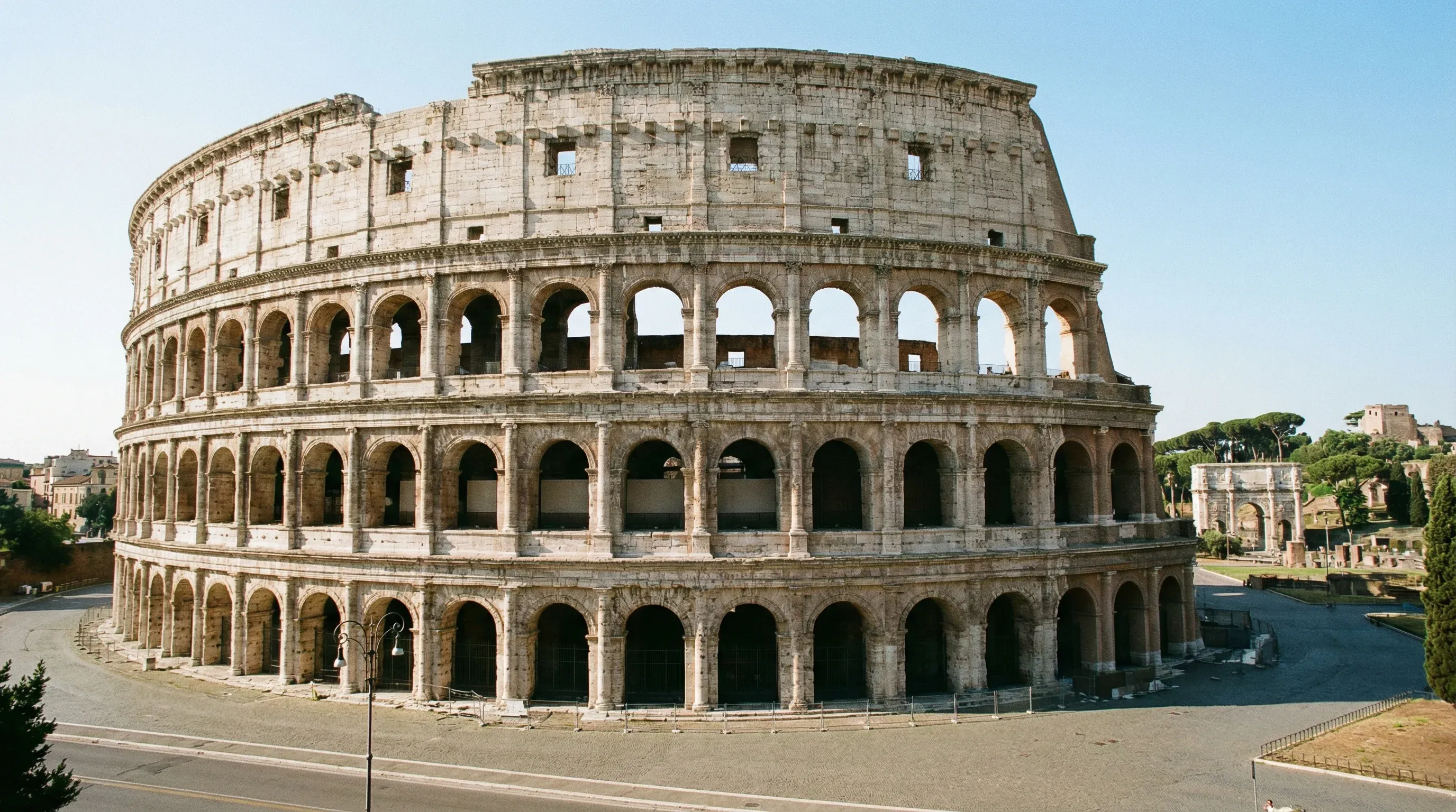 The ancient stone exterior and tiered arches of the Roman Colosseum under a bright, clear sky.
