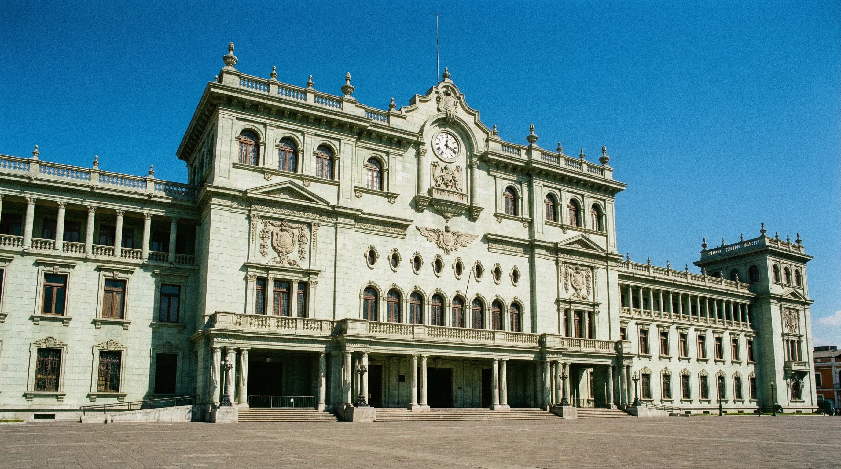 The ornate green stone National Palace of Culture building under a blue sky in central Guatemala City.
