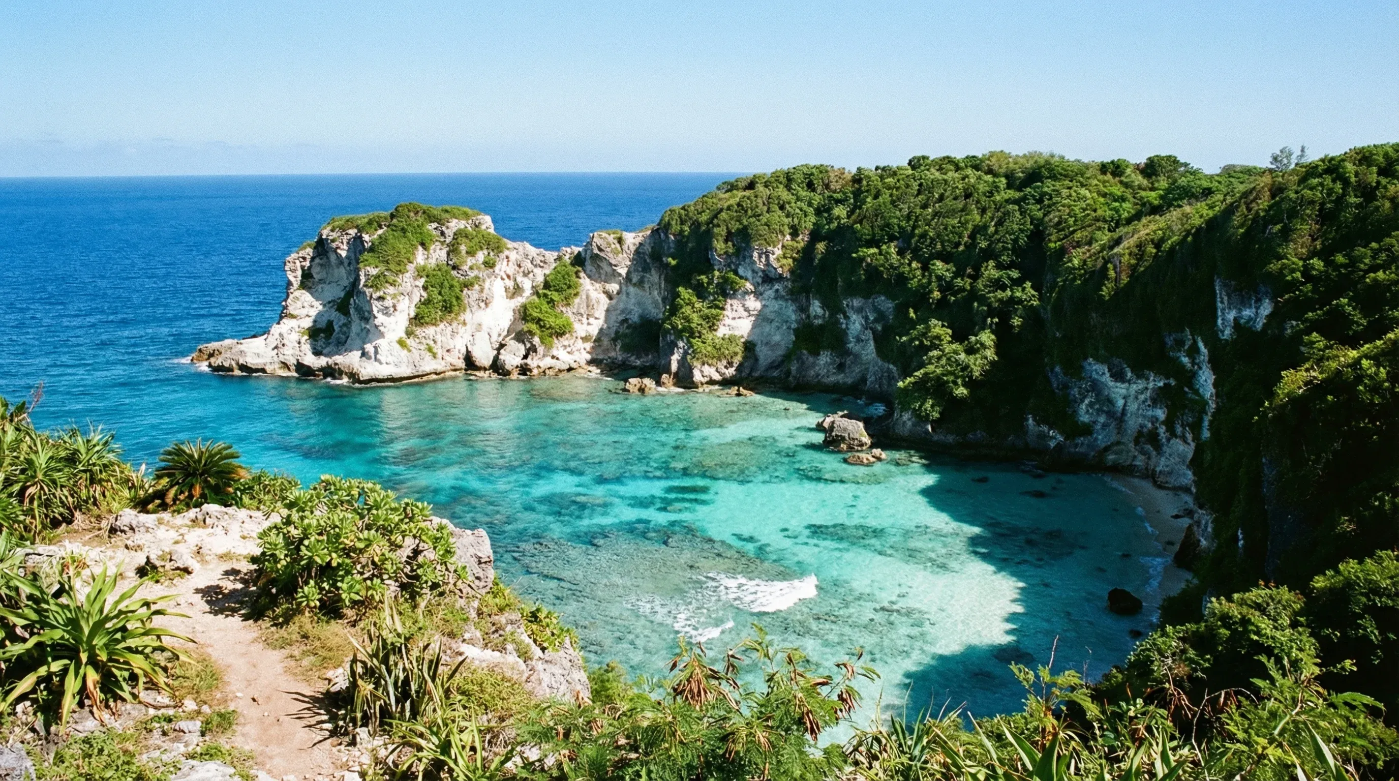 An elevated view of Bird Island sitting in a turquoise bay surrounded by limestone cliffs on Saipan.